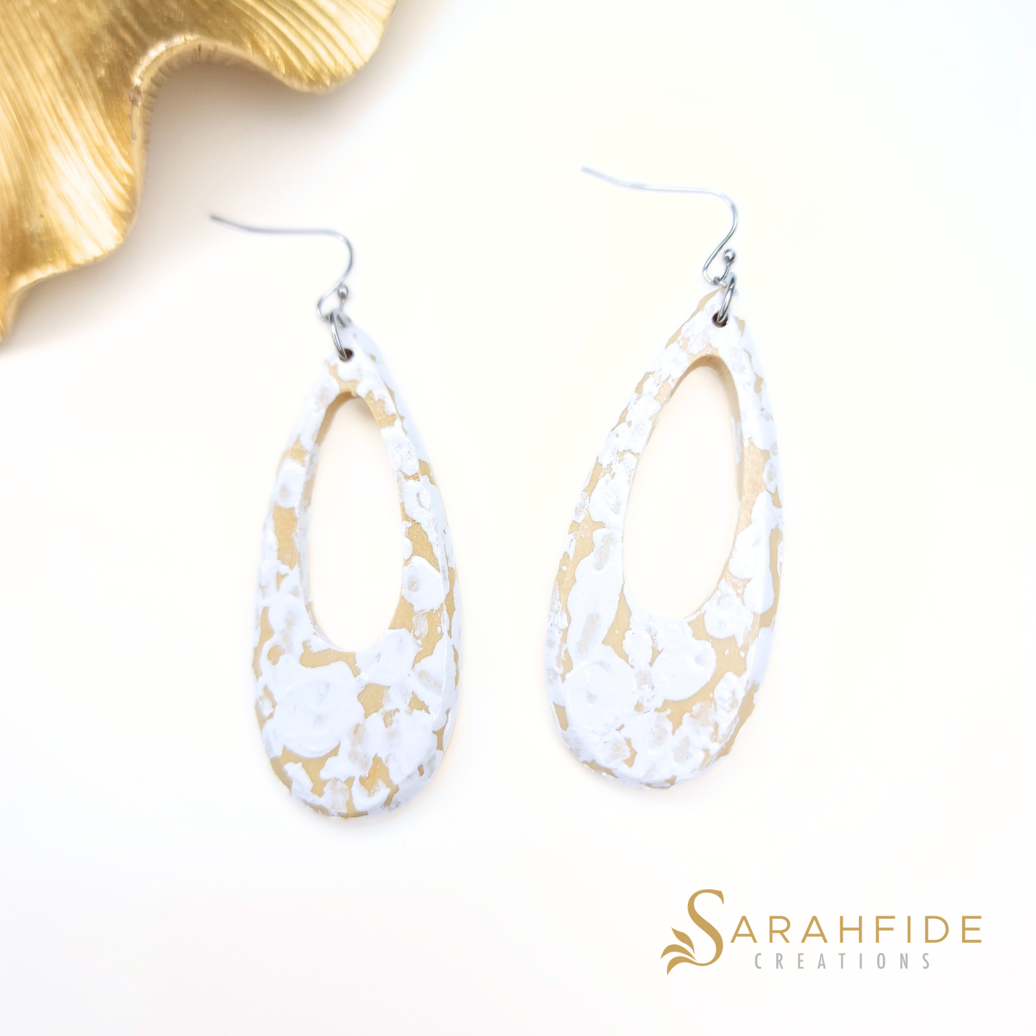 White and tan coastal drop earrings laid flat