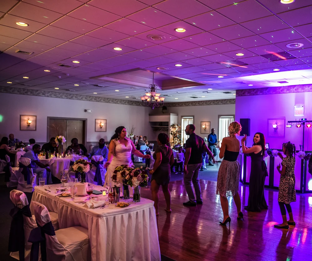 Wedding guests dancing together under purple event lighting