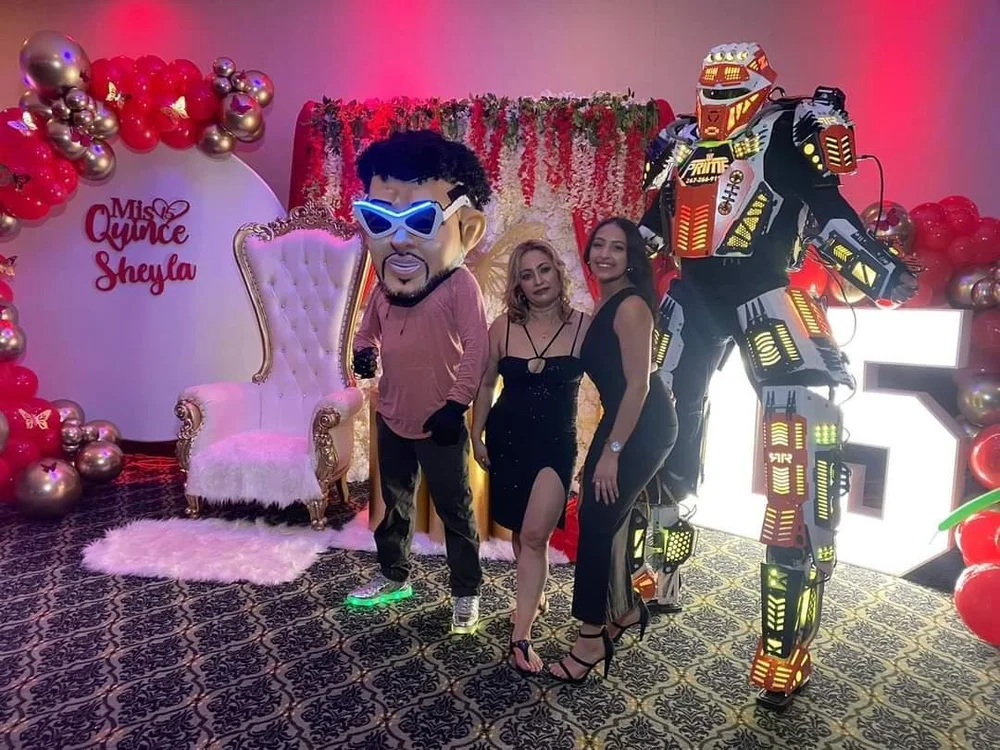 Party guests celebrating beside the Turn Up Robot and a costumed performer