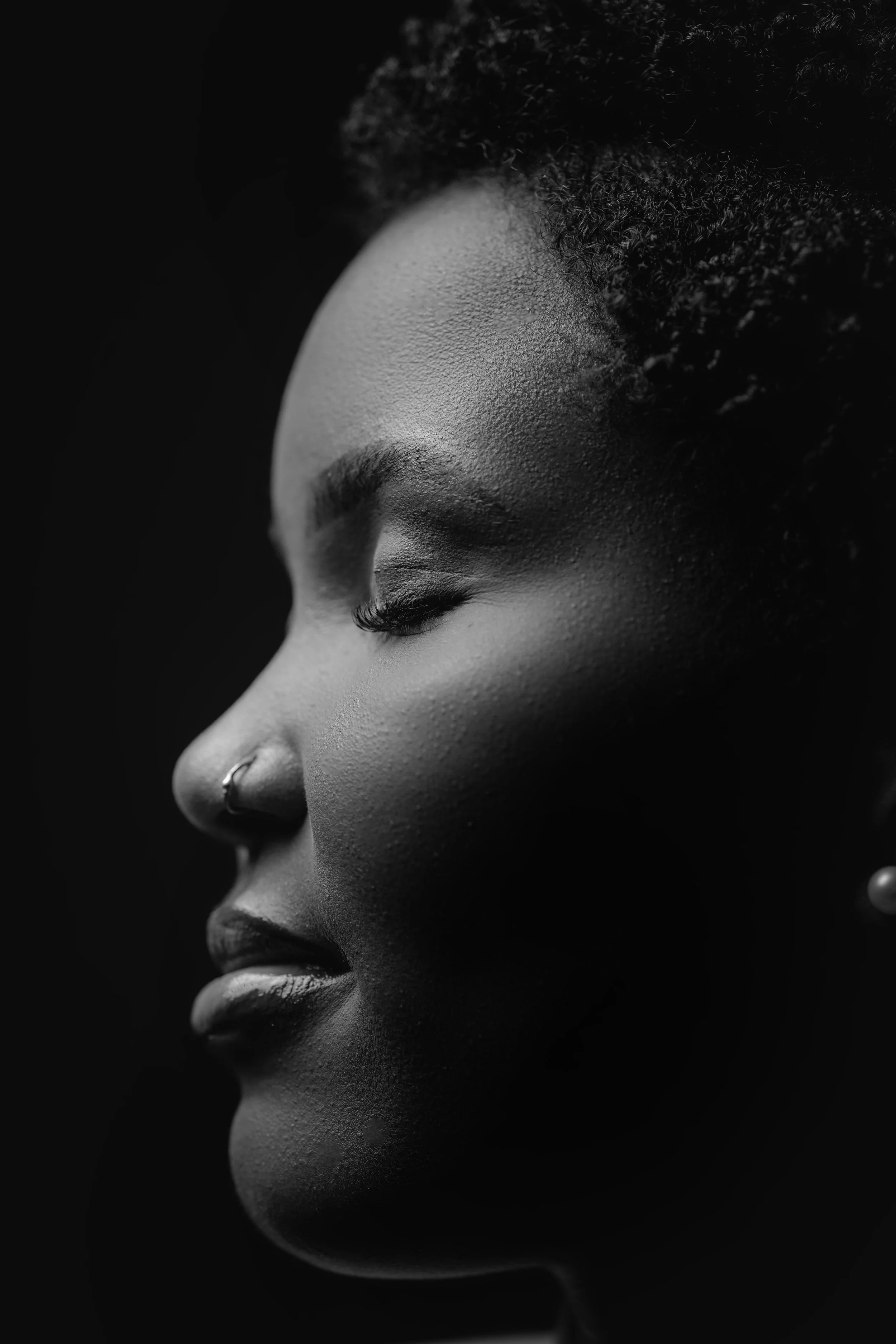 A black and white image of a Black woman's profile. She has a peaceful expression.