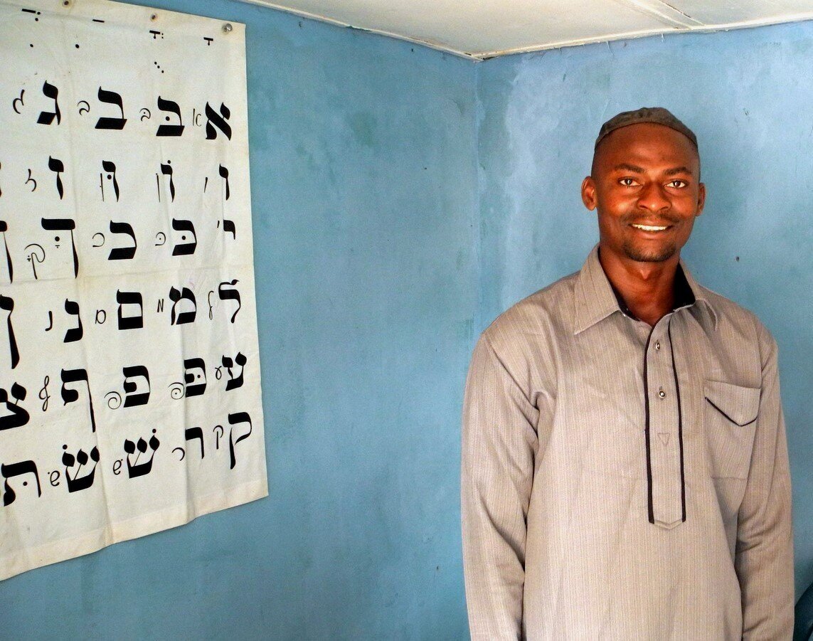 Izuchukwu Onuchukwu standing beside the letters of the Hebrew alphabet on the outskirts of Abuja, Nigeria. Photo — Shai Afsai