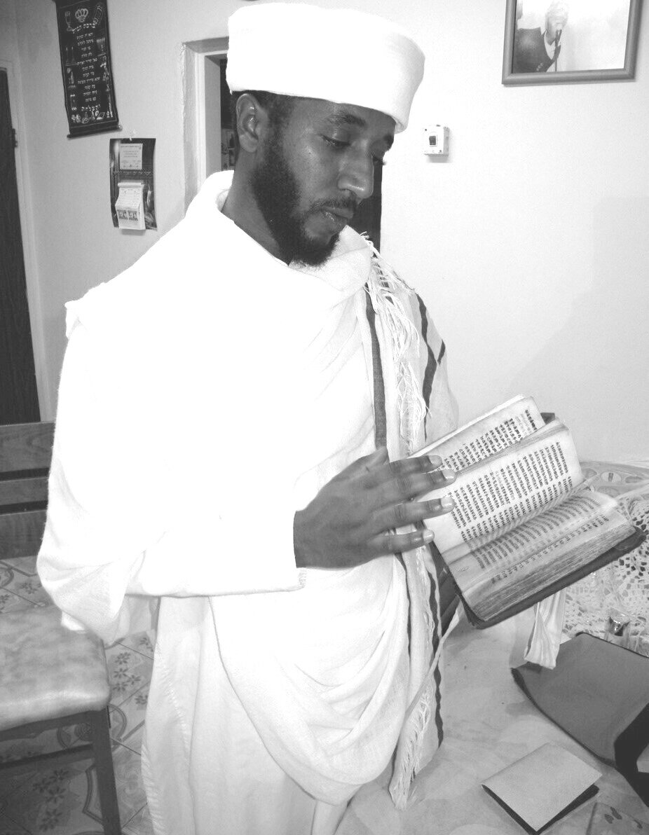 At his home in Karmiel, northern Israel, Qes Efraim Zion-Lawi examines a Jewish book from Ethiopia that his parents concealed while in Sudan. Photo — Shai Afsai