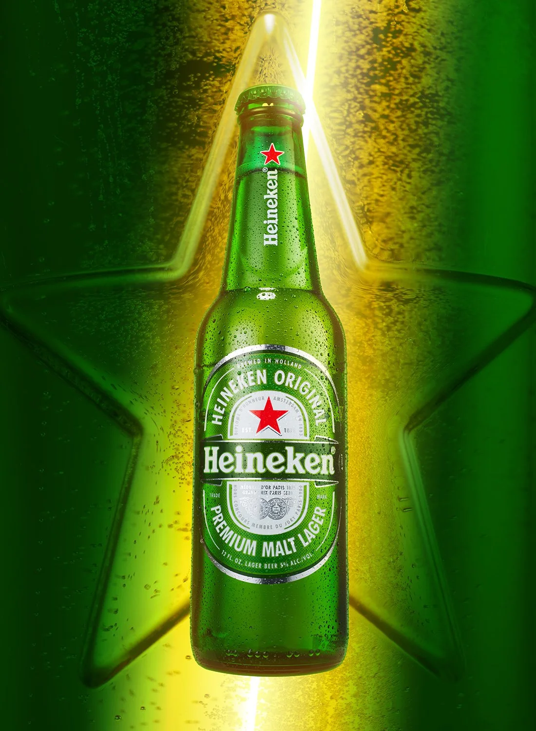Studio still life image of a chilled Heineken bottle with condensation against a glowing green star background, photographed by NYC beverage photographer Takamasa Ota.