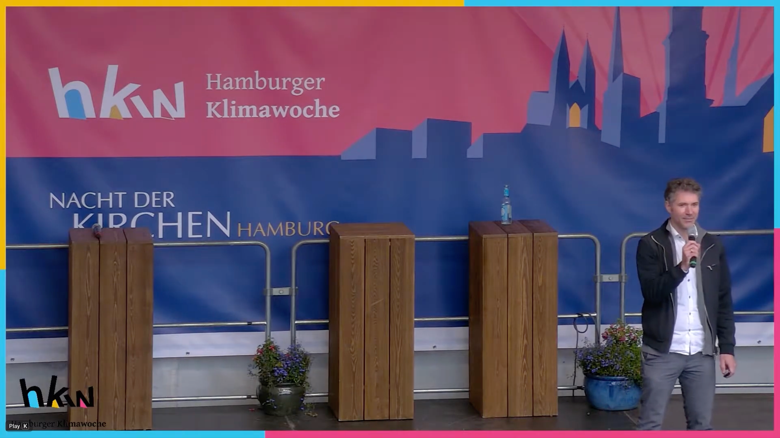 Lars Zimmermann von CITIES FOR FUTURE vor Plakatwand Klimawoche 2021 während seines Vortrages, mit Mikrophon