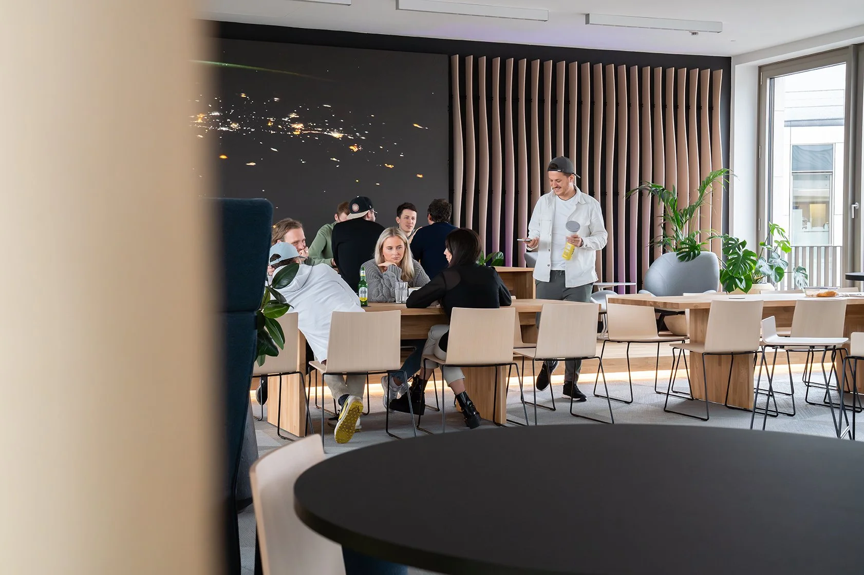 Dentsu Office: Konferenzraum mit Stühlen, Tisch und Menschen, die sich unterhalten. Themenbereich: Interiorgestaltung, Innenarchitektur, Placemaking.