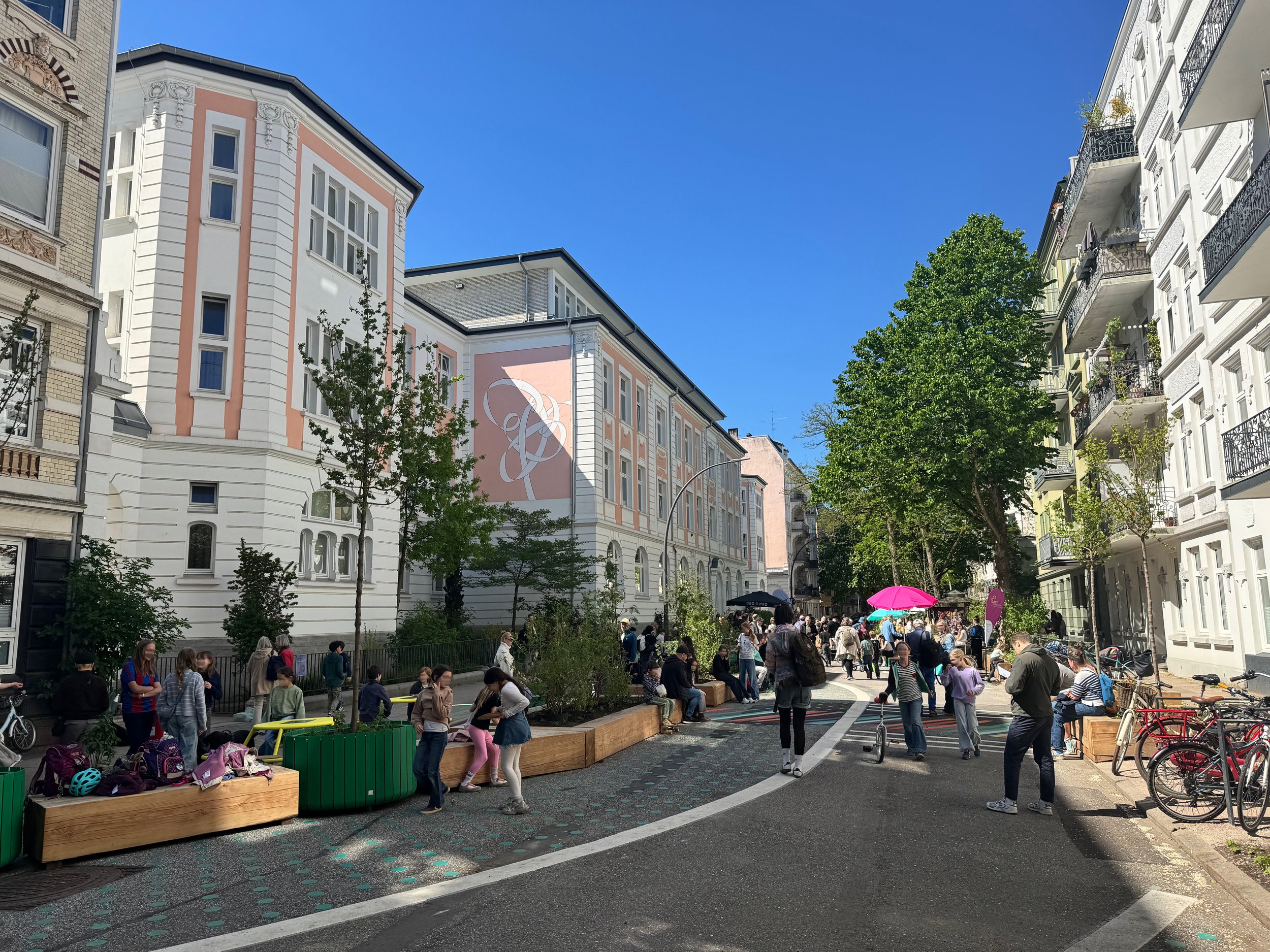 Foto der ersten Schulstraße in Hamburg Eimsbüttel, Rellinger Straße, vom 8. Mai 2026, dem Eröffnungstag. Bunte Markierungen auf der Straße, viel Sitzgelegenheiten und viele Menschen/Kinder.