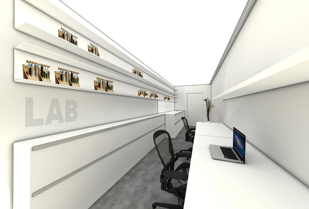 Ein modern eingerichteter Arbeitsraum mit weißen Wänden, mehreren schwarzen Bürostühlen, einem Laptop auf einem langen weißen Tisch, vertikalen Regalen mit kleinen goldfarbenen Objekten, und dem Wort 'LAB' an der Wand.