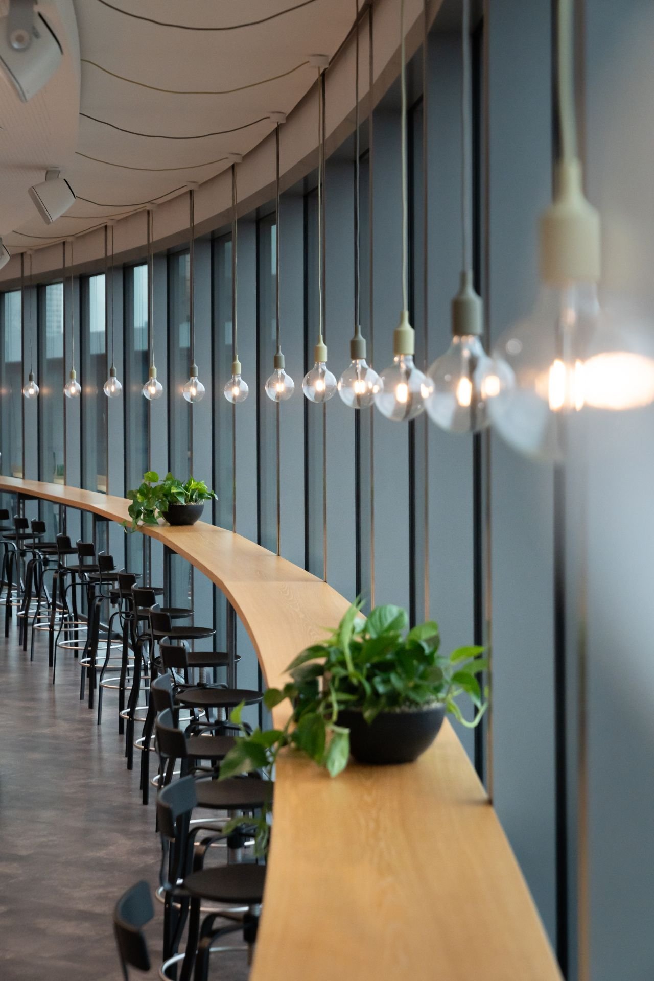 Dentsu Office: Ein Raum mit einer rund gebogenen Wand vor der viele Lampen hängen. Themenbereich: Interiorgestaltung, Innenarchitektur, Placemaking.