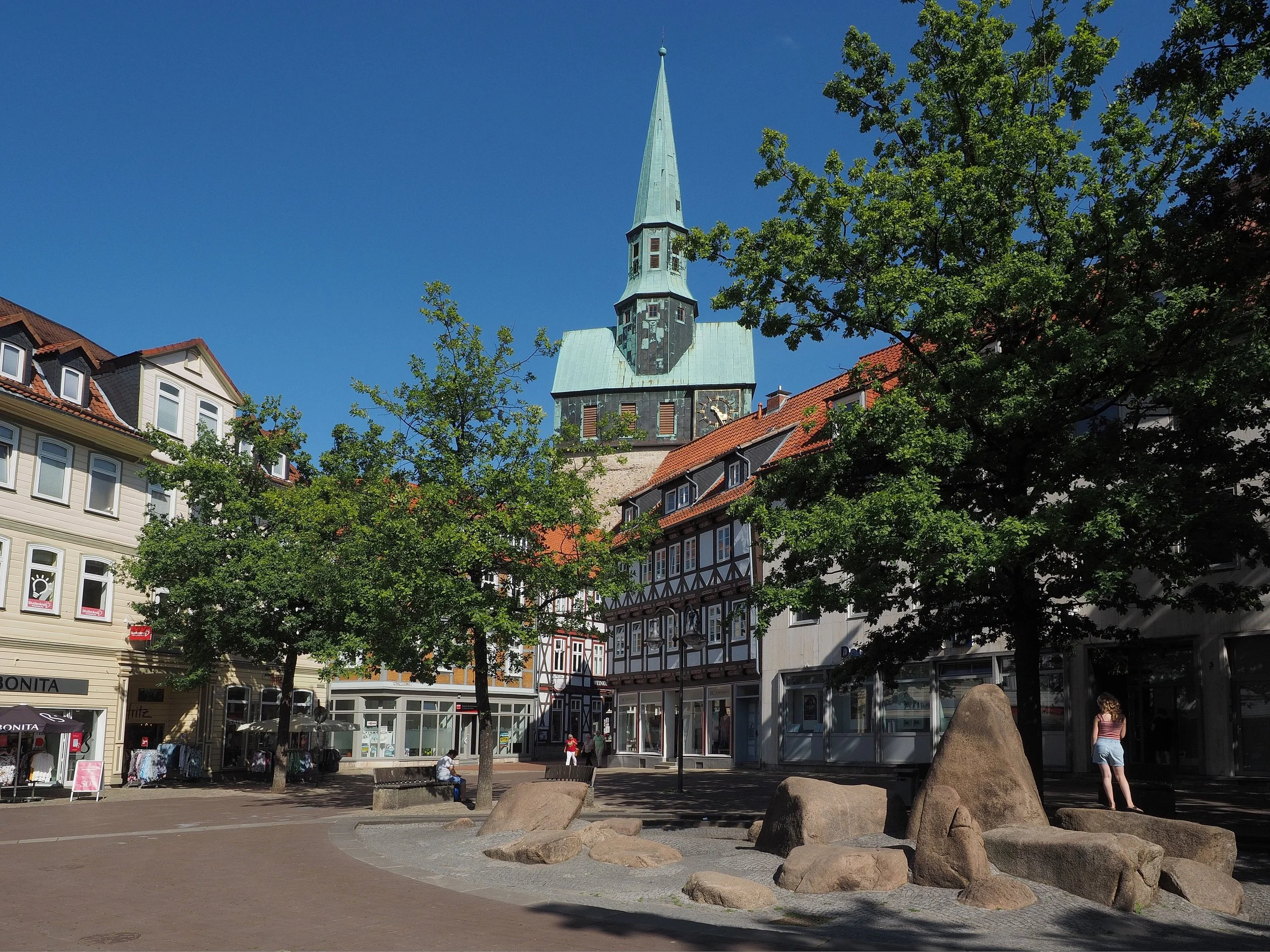 Projekt Innenstadtvision Osterode. Außenaufnahme Osterode, in der Mitte große Steine, dahinter Kirchturm mit grünem Kupferdach.