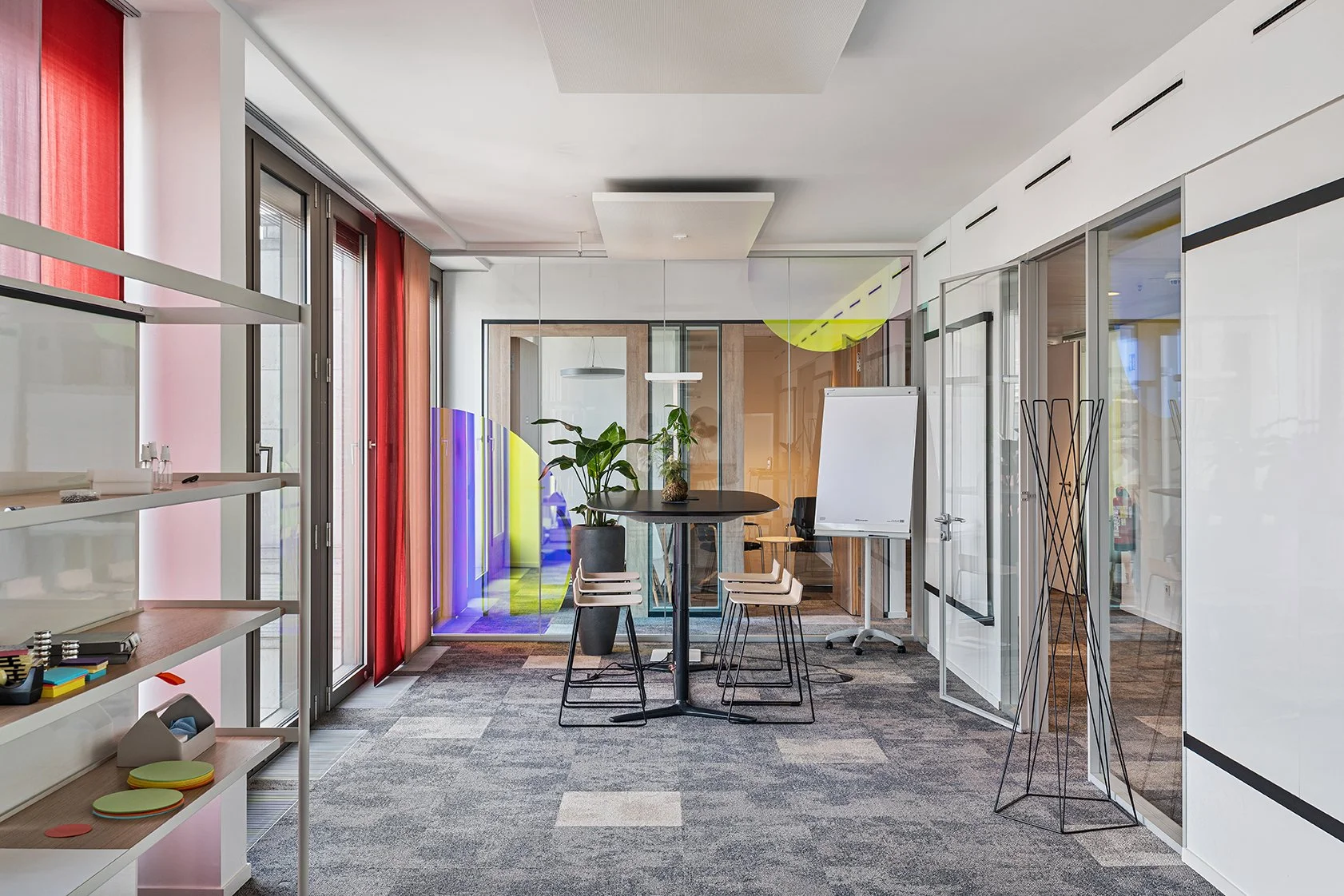 Dentsu Office: Blick in einen Raum mit einem runden Tisch, Stühlen und Flipchart am Ende des Raumes. Themenbereich: Interiorgestaltung, Innenarchitektur, Placemaking.