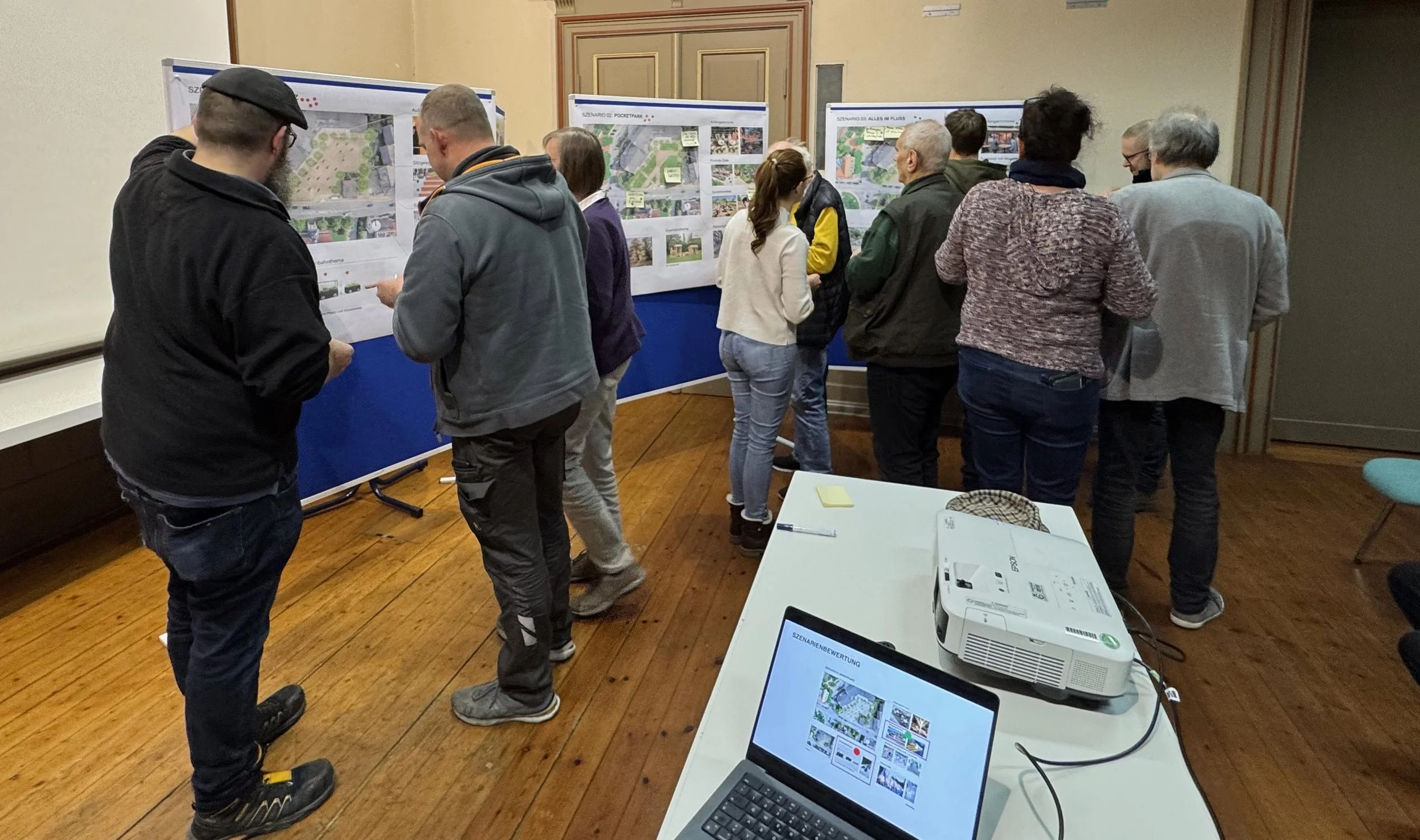 Foto vom Workshop im Rahmen des Projektes Aufwertung Maktplatz Vienenburg. Es sind meherere balue Tafeln zu sehen, vor denen Menschen stehen und auf den Tafeln sind Bilder und Post-its.