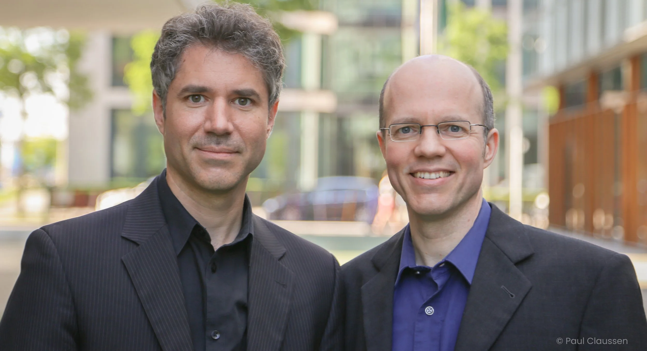 Links Lars Zimmermann und rechts Kai Zimmermann, unscharfer Stadthintergrund. Beide blicken direkt in die Kamera. Beide sind Co-Founder von CITIES FOR FUTURE.