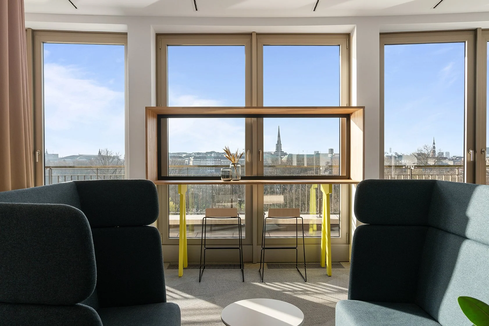 Dentsu Office: Blick in einen Raum mit Fenstern. Vorne schwarzer Sessel mit langen Seitenwänden. Themenbereich: Interiorgestaltung, Innenarchitektur, Placemaking.