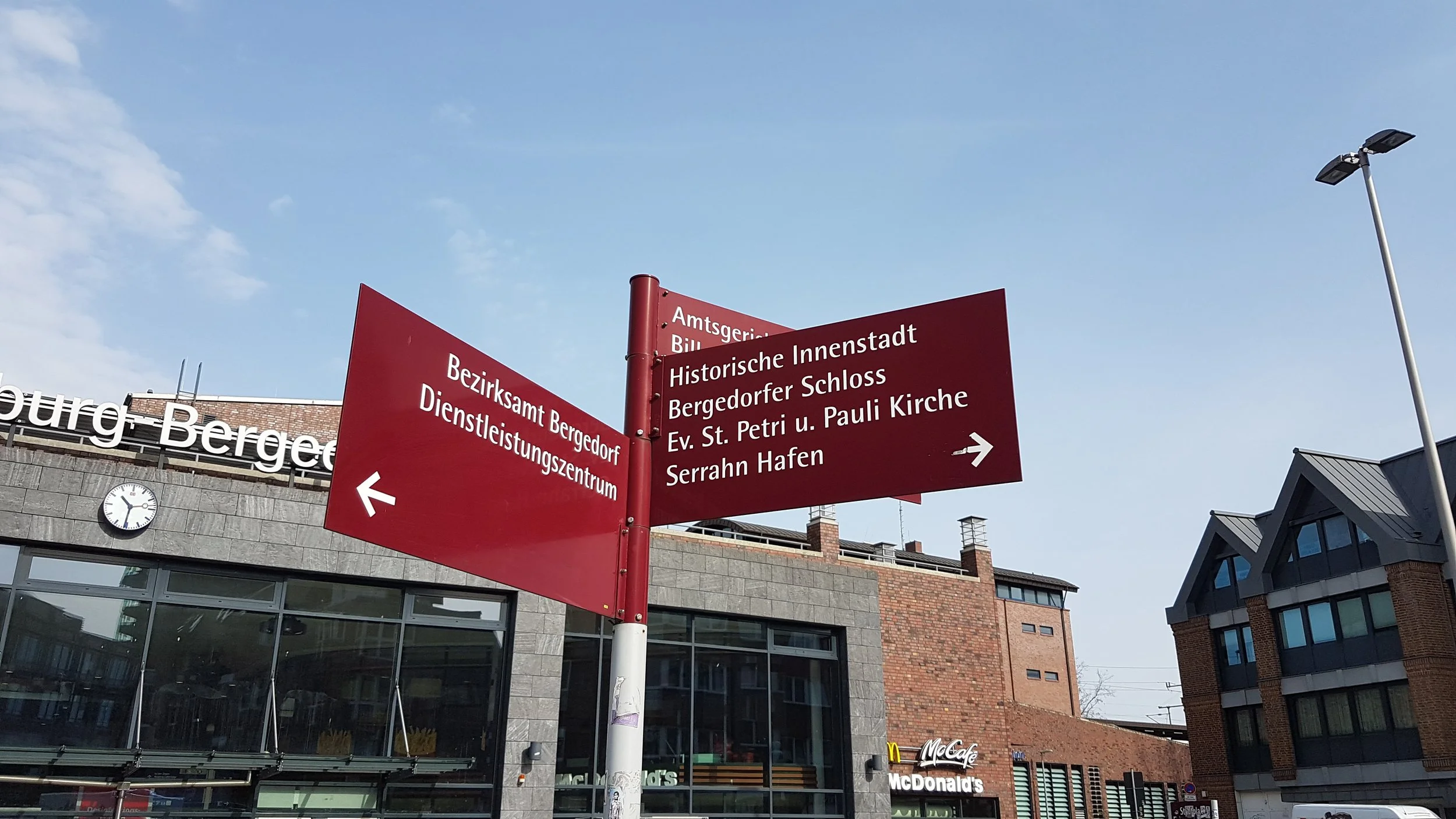 Vor dem Bahnhof Bergedorf, Hinweisschilder in dunkelrot auf z.B. Bezirksamt Bergedorf.