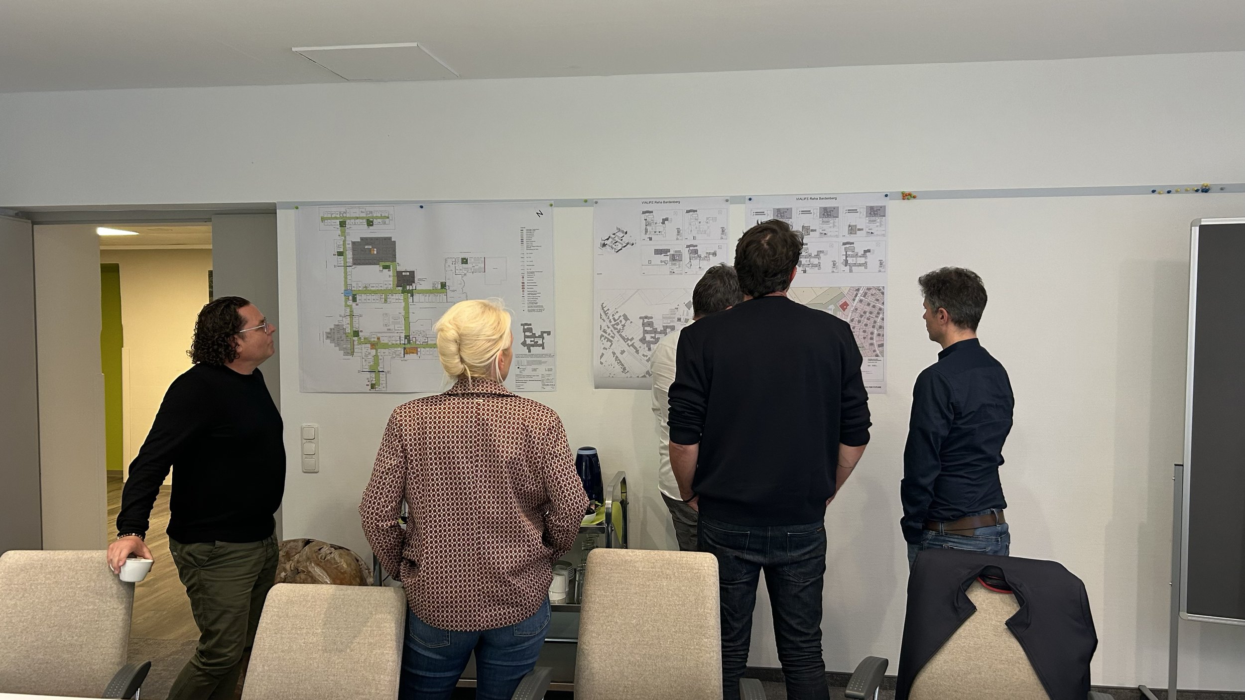 Foto eines Workshops im Projekt Vialife Campus Bardenberg. Personen stehen vor einem Whiteboard mit Plänen und Notizen.