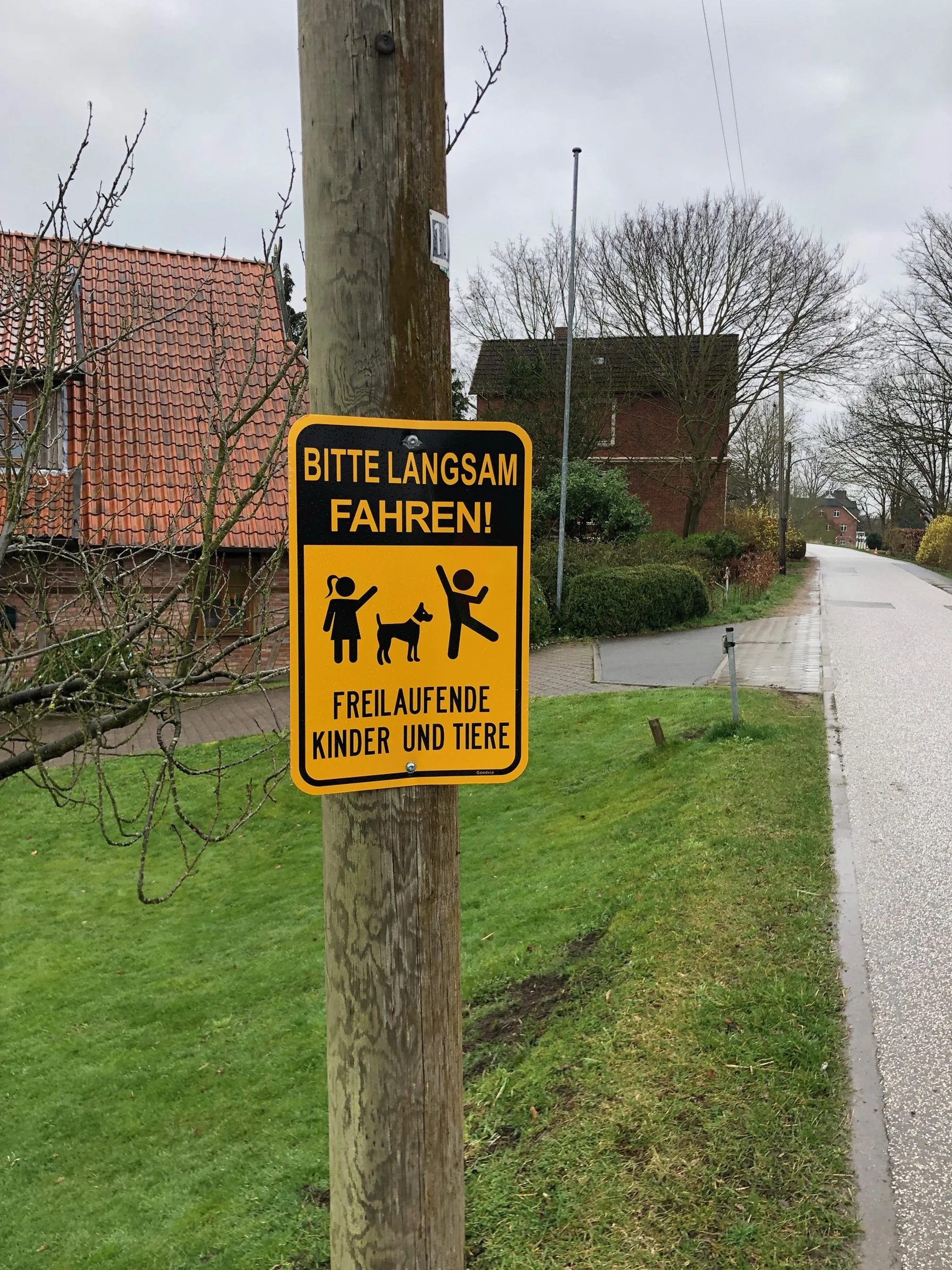Foto Vier- und Marschlande. Oranges Schild mit der Aufschrift "Bitte langsam fahren, freilaufende Kinder und Tiere". Symbole von Kindern und Hund. Projekt Mobilitätskonzept Vier- und Marschlande von CITIES FOR FUTURE.
