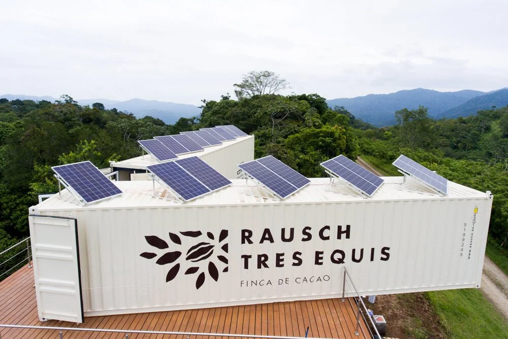 Ein umgebauter LKW mit Solarzellen auf dem Dach, im Hintergrund Wald und Berge, Beschriftung: Rausch Tres Equis, Finca de Cacao.