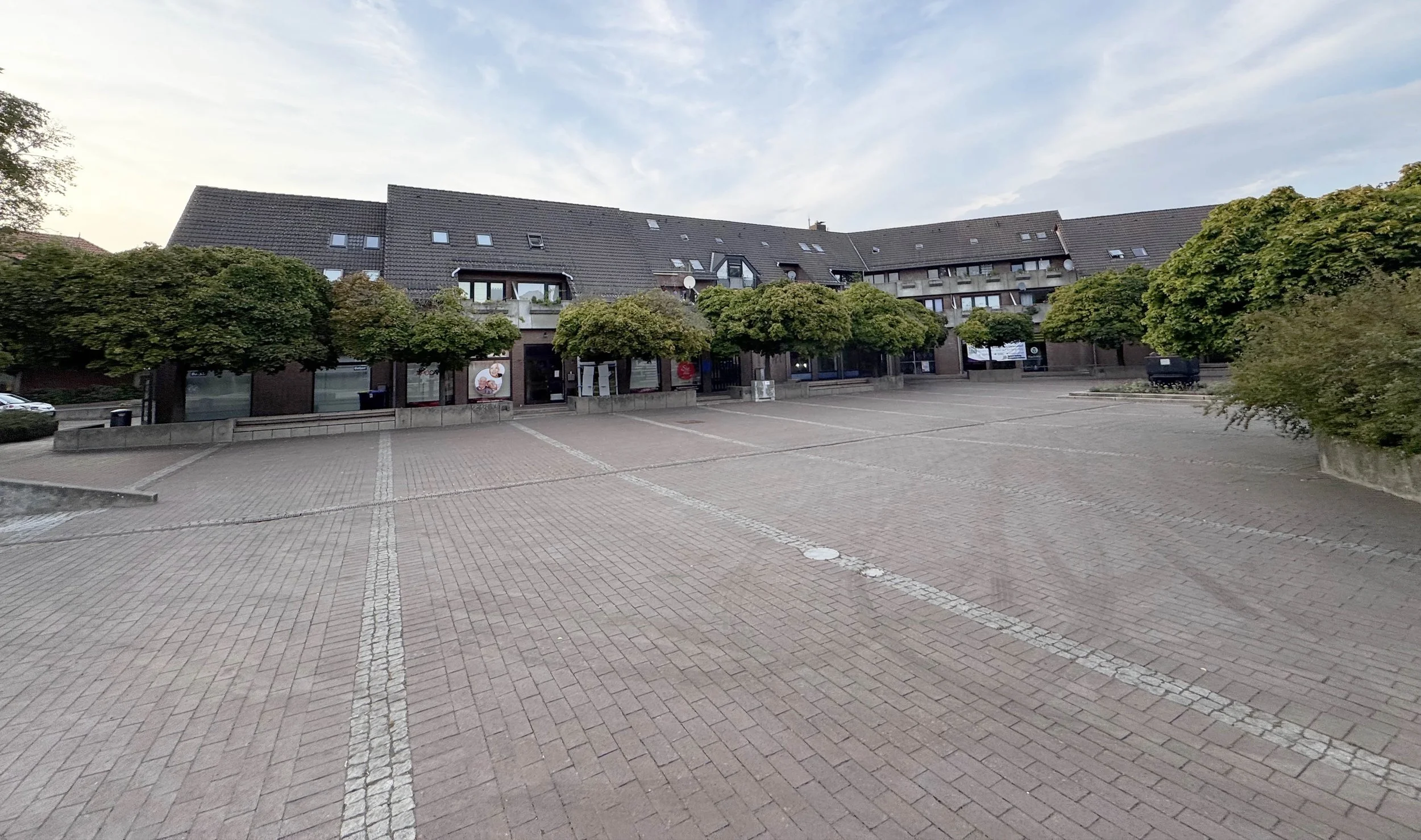 Vienenburger Marktplatz, vorne ein leerer gepflasterter Platz, hinten Bäume und Gebäude.