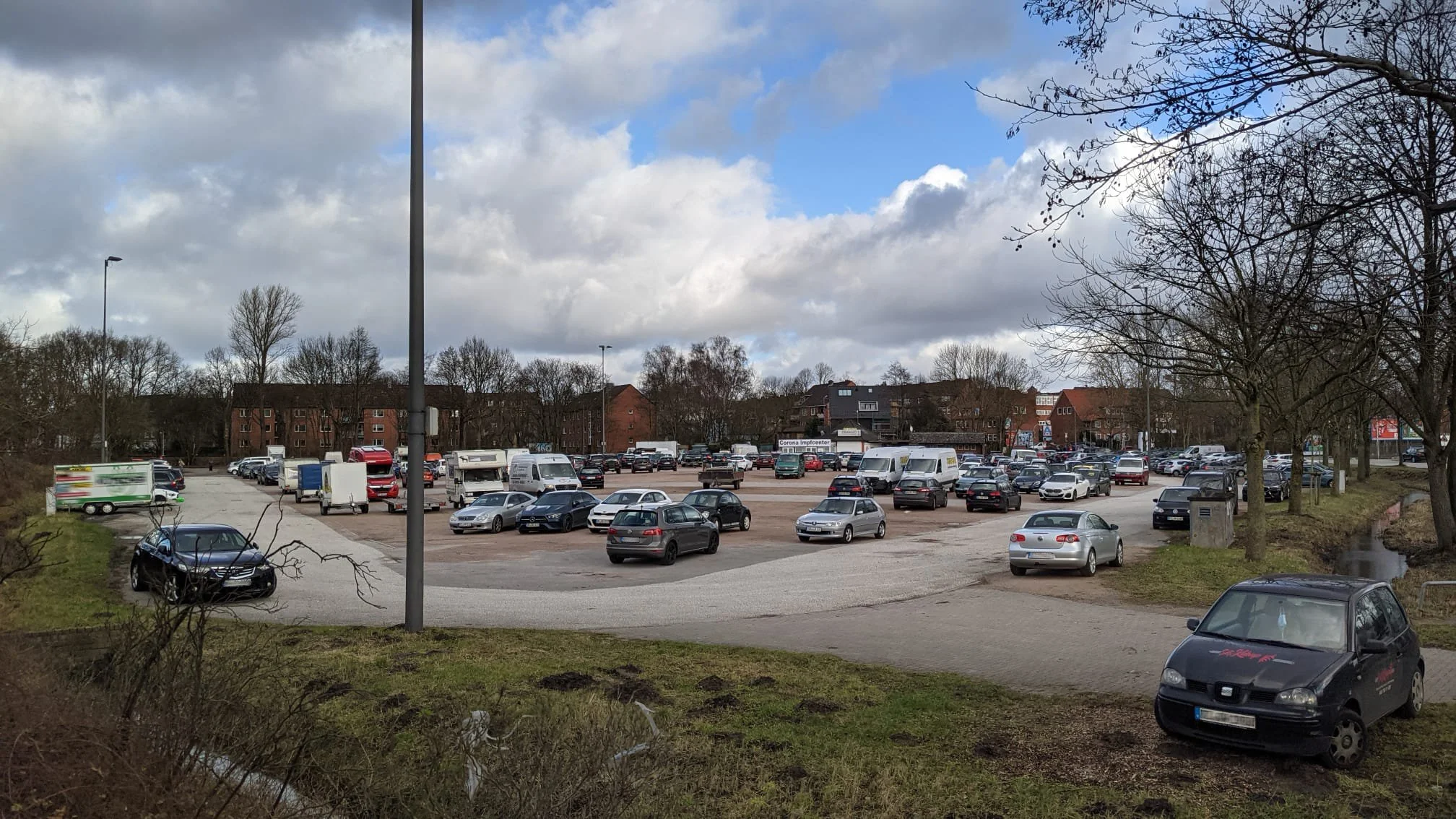 Frascatiplatz in Hamburg Bergedorf. Viele parkende Autos und im Vordergund kleine Rasenfläche am Rand.