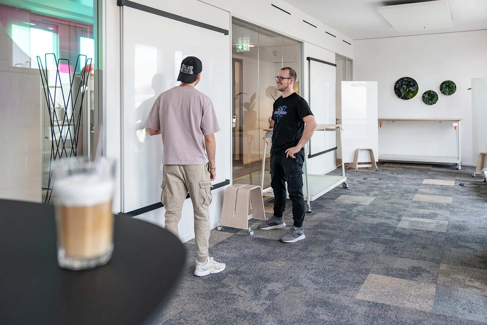 Dentsu Office: Blick auf eine Raum in dem 2 Männer vor einem Whiteboard stehen. Themenbereiche: Interior, Aufenthaltsqualität, Placemaking.
