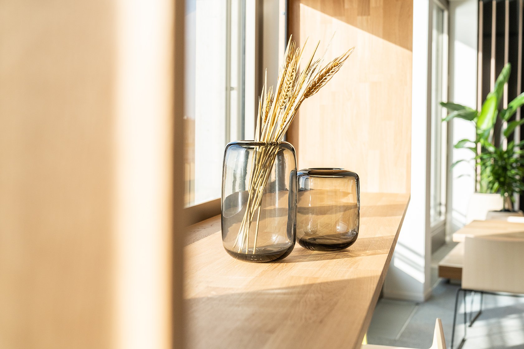 Dentsu Office: Eine Fensterbank aus Holz mit zwei runden Vasen unterschiedlicher Größe. In der großen Vase befinden sich ein paar Halme von Weizen. Themenbereich: Interiorgestaltung, Innenarchitektur, Placemaking.