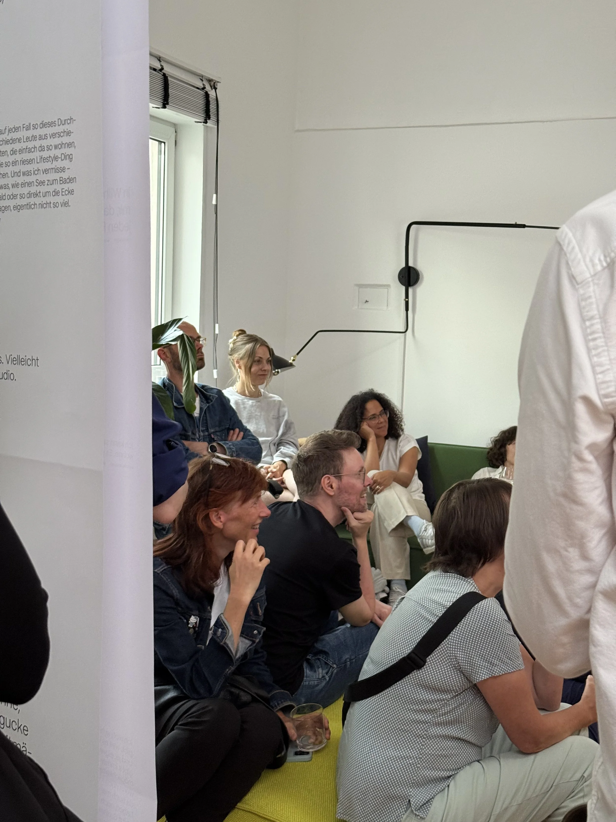 Menschen sitzen im Ausstellungsraum, einige lachen und unterhalten sich. Sie hören der Präsentation der Umfrageergebnisse zu. Hamburg Sustainability Week 2026. Ausstellung im Loft141.