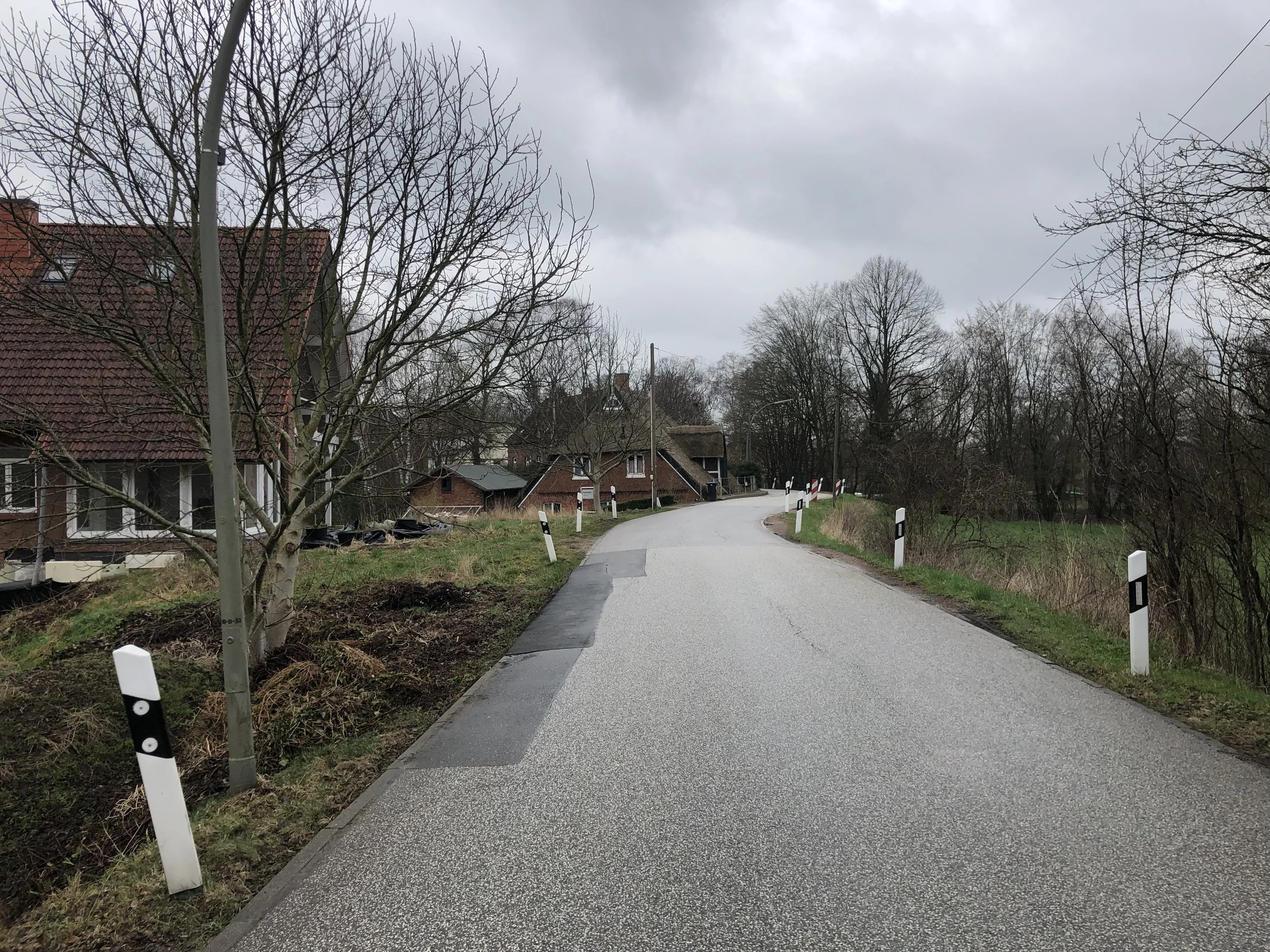 Foto Vier- und Marschlande. Ländliche Straße mit schwarz-weißen Begrenzungspfosten an den seiten. Projekt Mobilitätskonzept Vier- und Marschlande von CITIES FOR FUTURE.