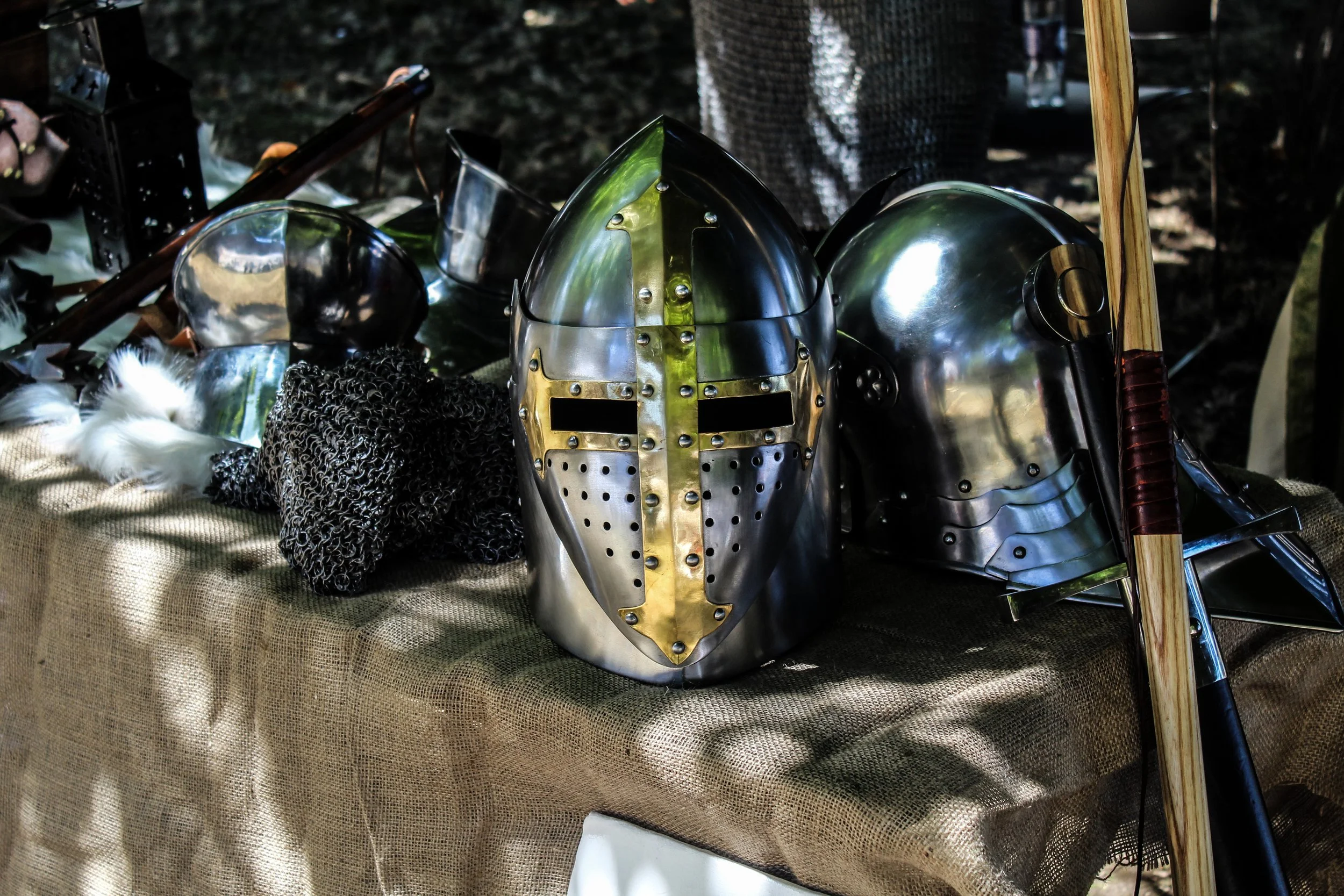 Medieval armor helmets and weapons displayed on a table.