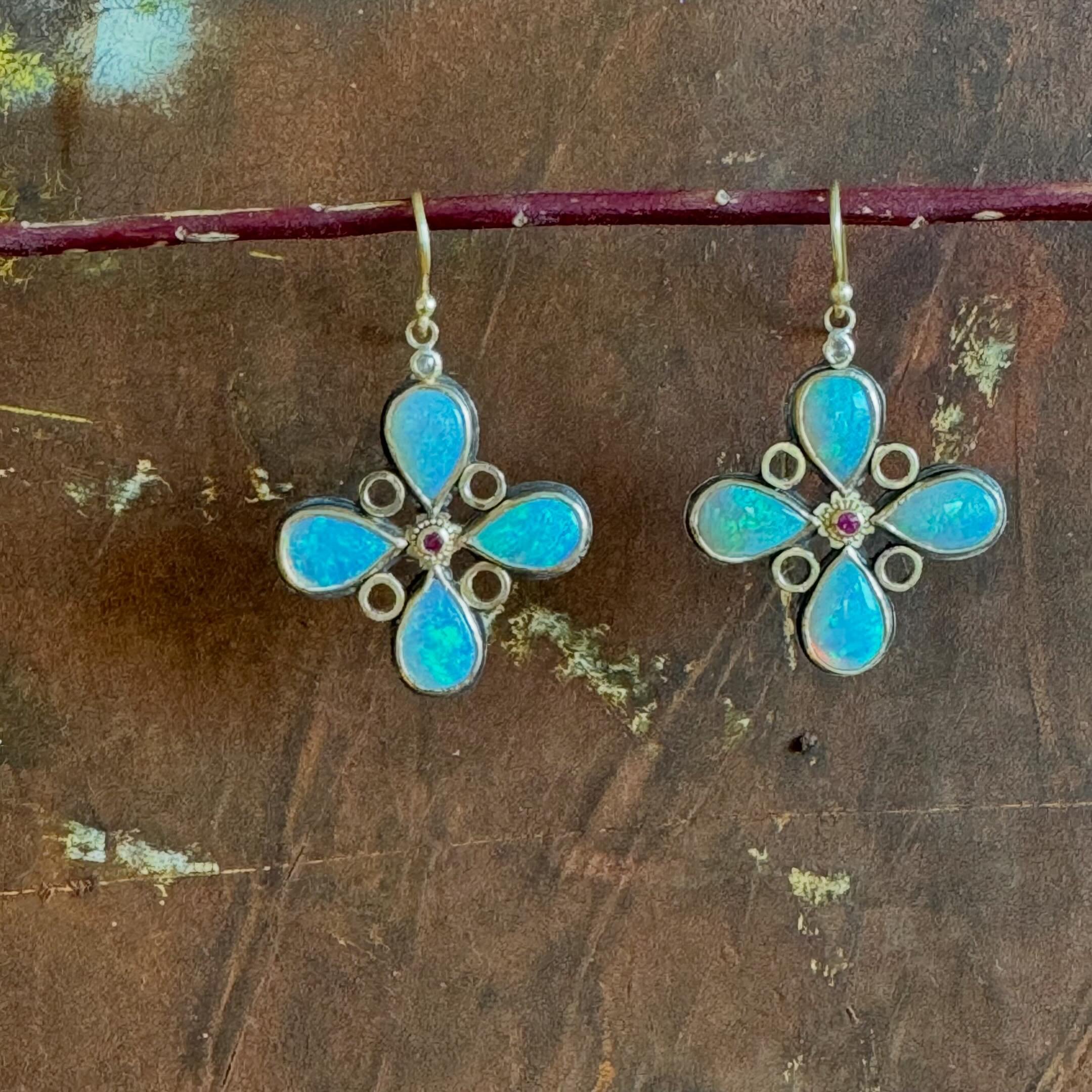 Opals are made of tiny spheres of silica with tiny water molecules filling the spaces between the spheres. The beautiful play of colors are produced by the diffraction of light as it moves through the spheres of silica and water. Opal earrings with r