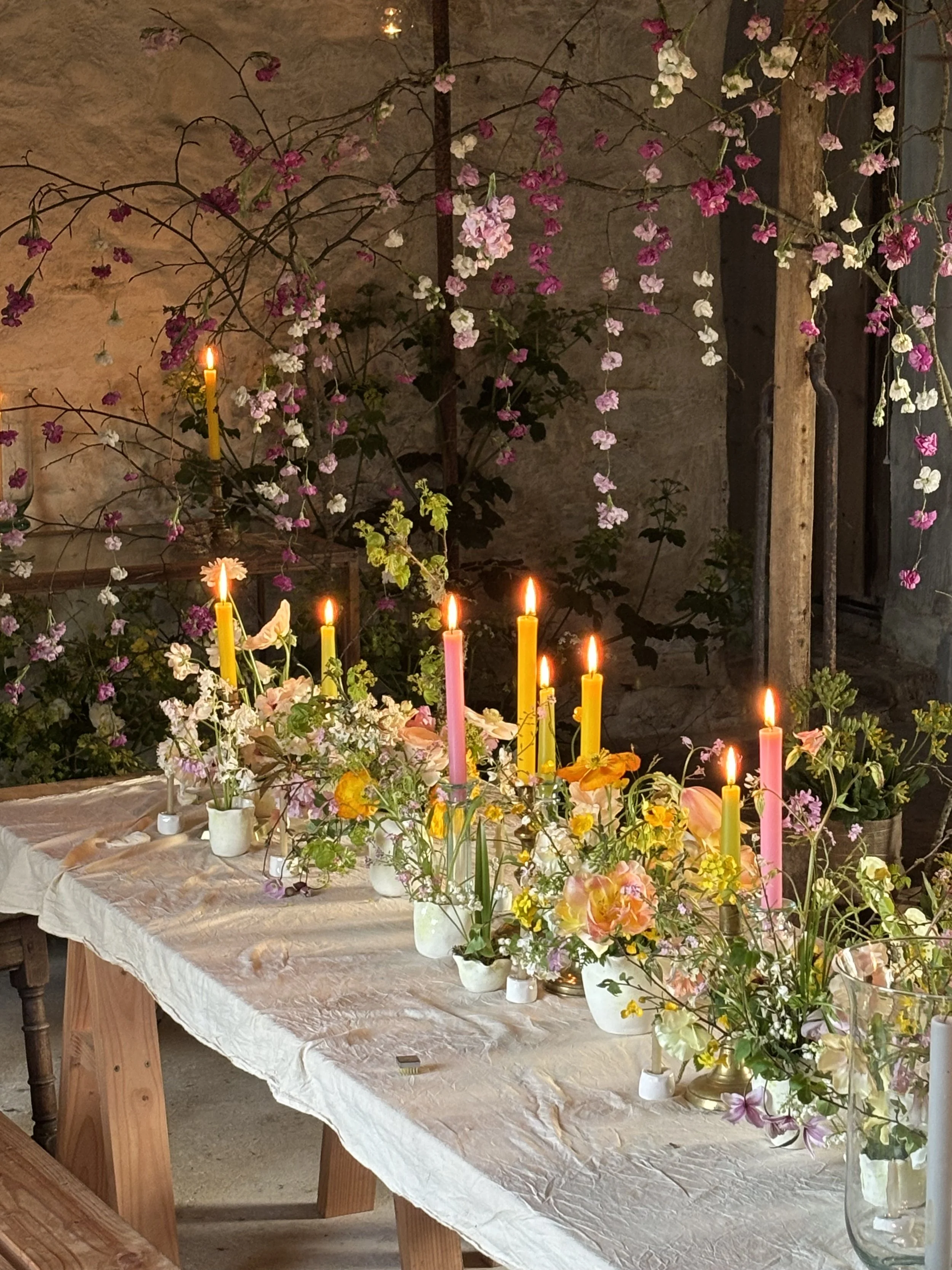 A table decorated with flowers and lit candles in a rustic setting.