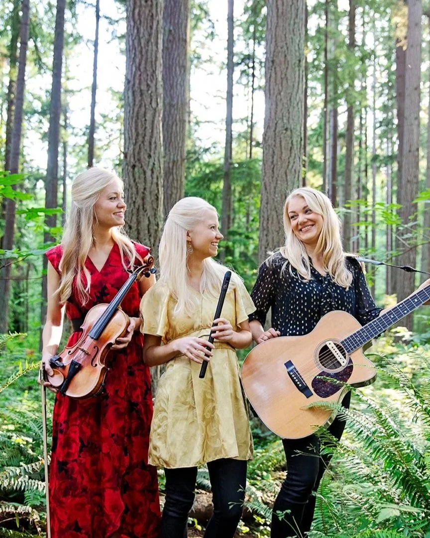 The Gothard Sisters pose in the forest with their instruments for the cover of their Christmas album, "A Celtic Christmas" in 2023. Willow (left) holds a violin, Solana (center) holds a pennywhistle, and Greta (right) holds a guitar.