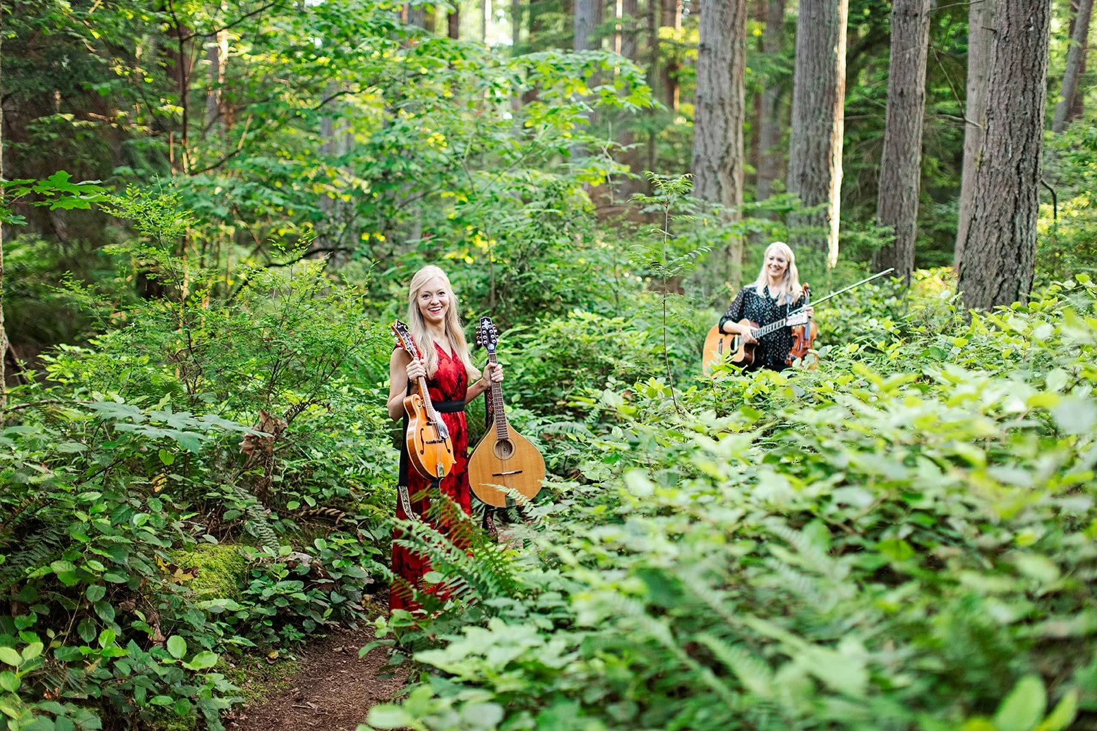 The Gothard Sisters stop in the woods with hands full of instruments. Willow (left) holds both a mandolin and an octave mandolin. Greta (right) holds a guitar and a fiddle. Photo for the album "A Celtic Christmas" from Art Chowder interview.