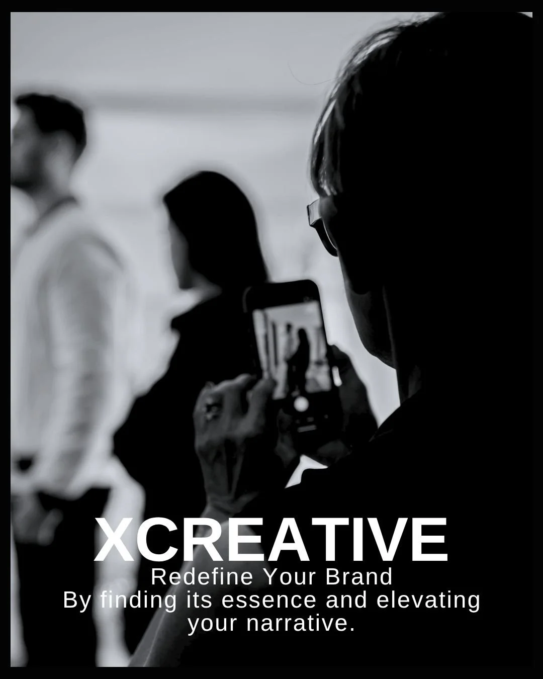 XCreaative A person taking a photo of two other people with a smartphone at an event. The image is in black and white.