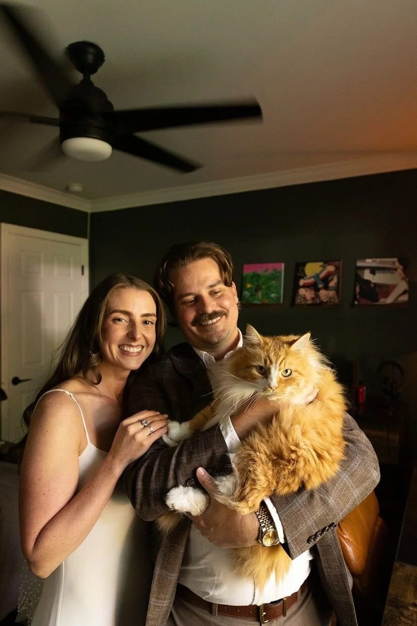 Couple who just got married posing with fluffy orange cat before going to The Goodyear House in Charlotte for reception