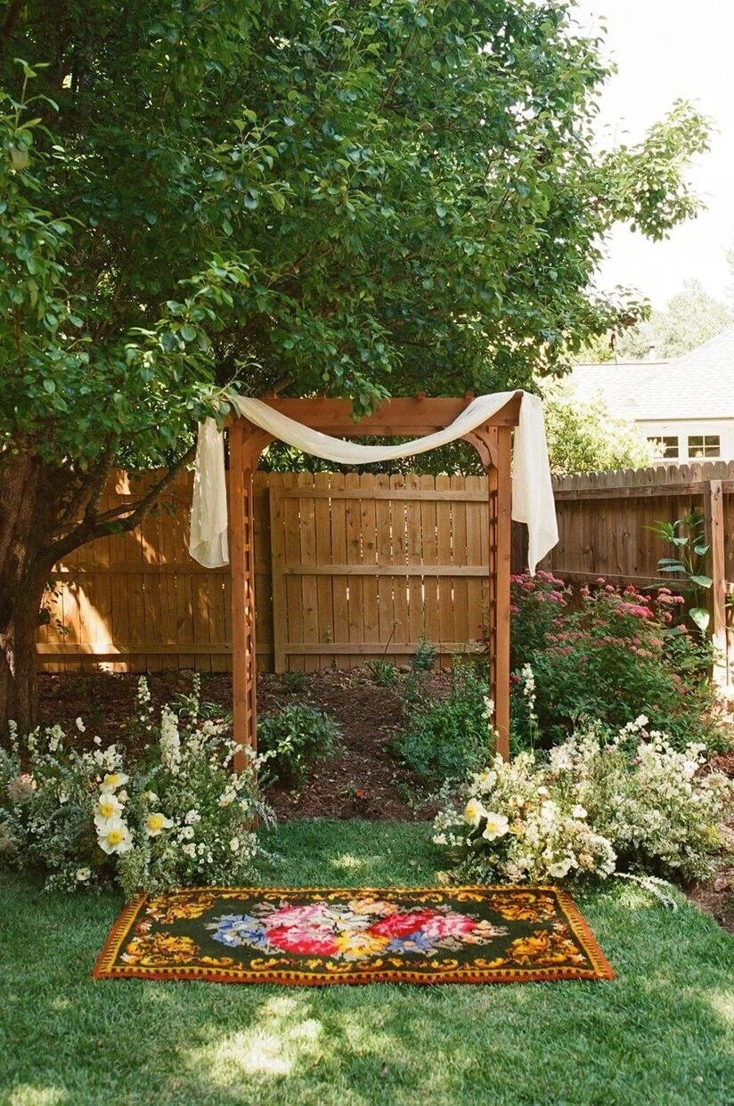 Wooden arch with colorful rug below it at a backyard wedding for a Goodyear House wedding in Charlotte, NC