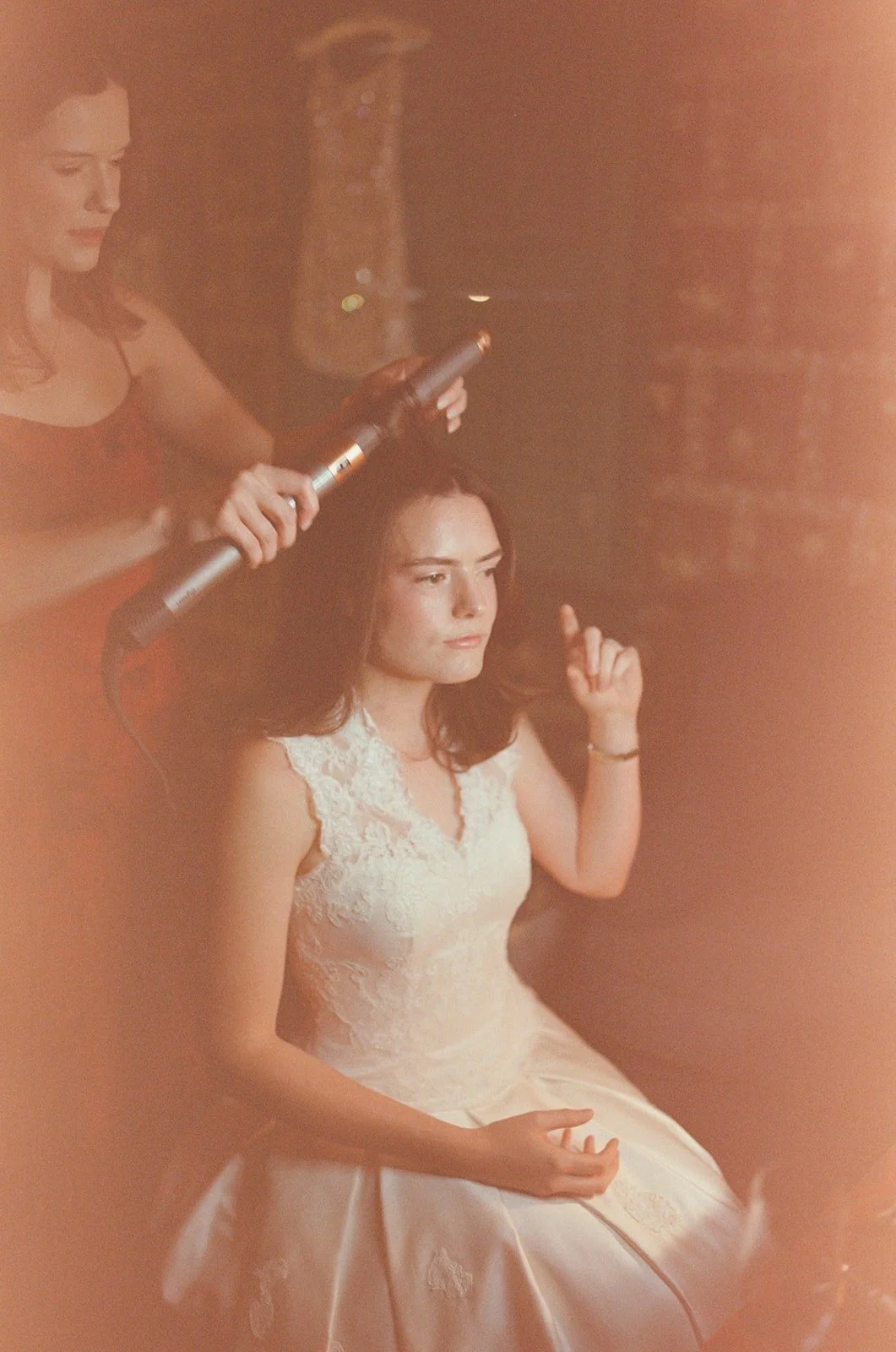 Friend curling bride's hair while she gets ready for a micro wedding in North Carolina