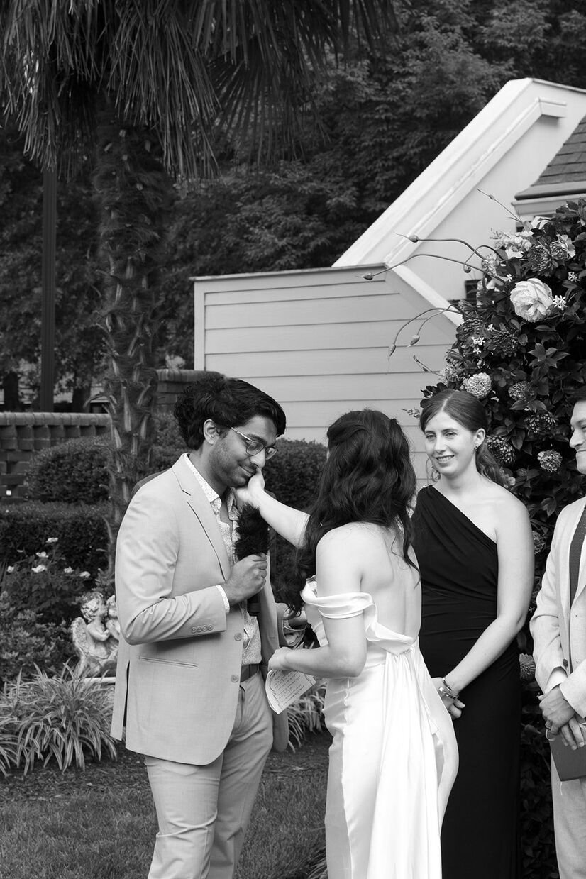 Bride holding grooms cheek as he says vows during ceremony at The Matthews House in Cary, NC.