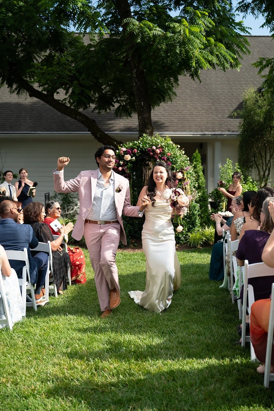 Bride and groom celebrating after vow exchange and walking back down the aisle at The Matthews House in Cary