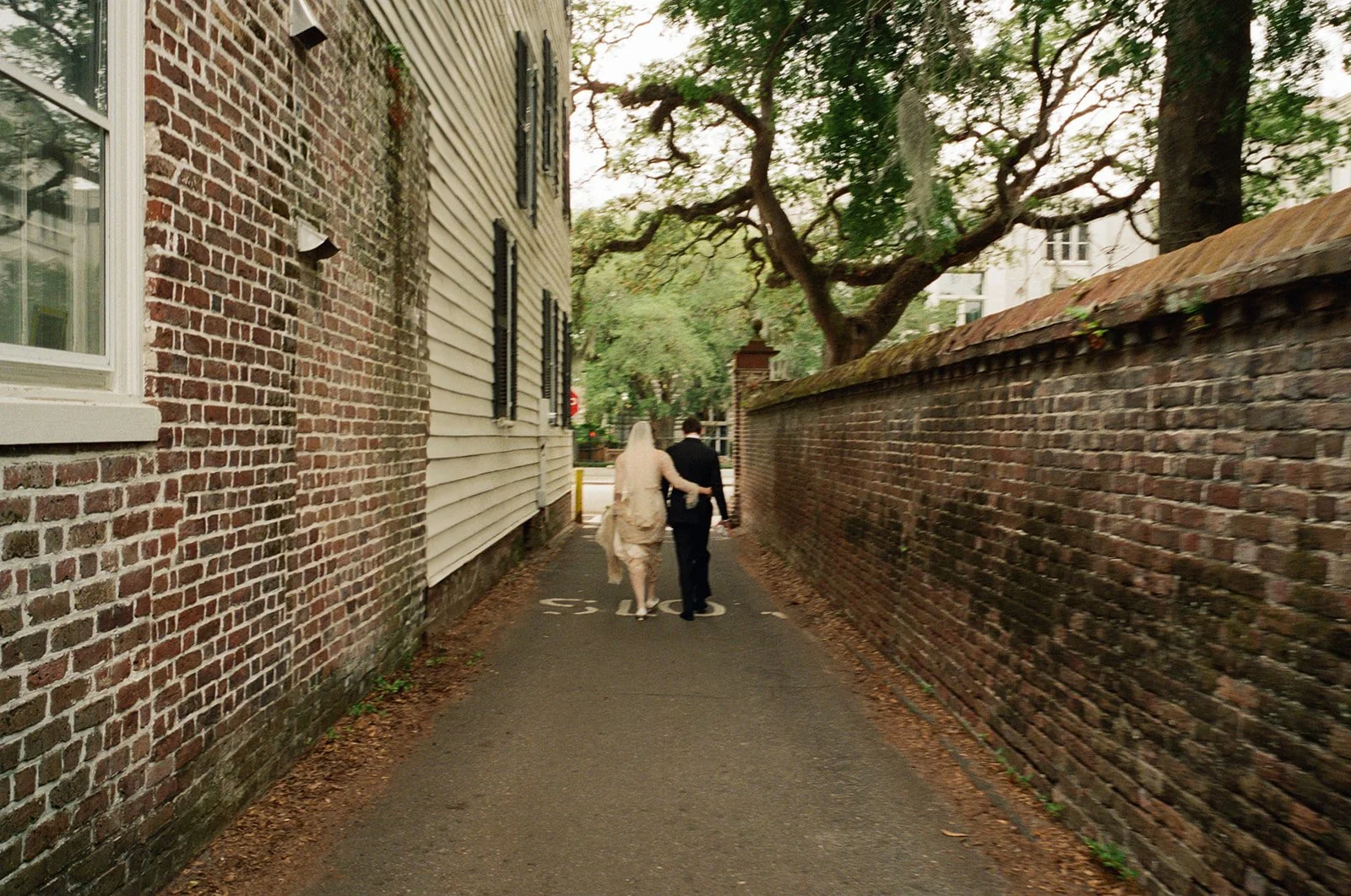 Bride and groom walking hand in hand through a historic Charleston alley after their Charleston wedding.