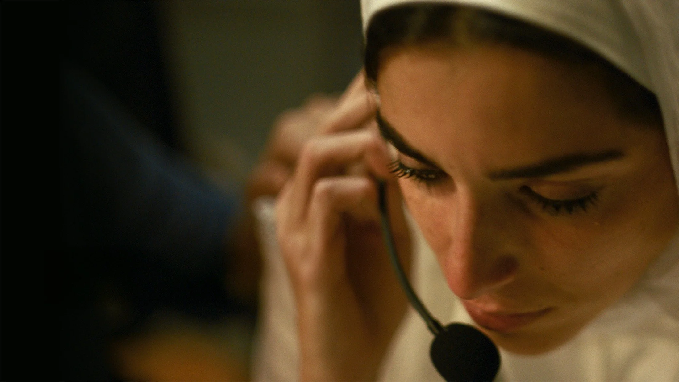 A woman in a hijab listens on a headset