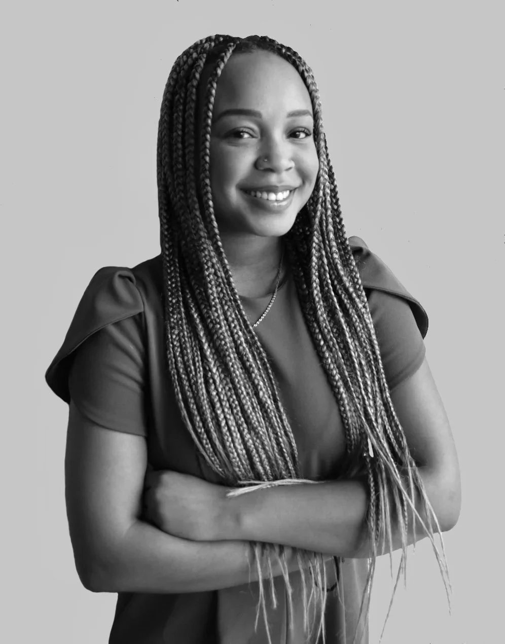 Black and white headshot of Laurie crossing her arms and smiling to camera