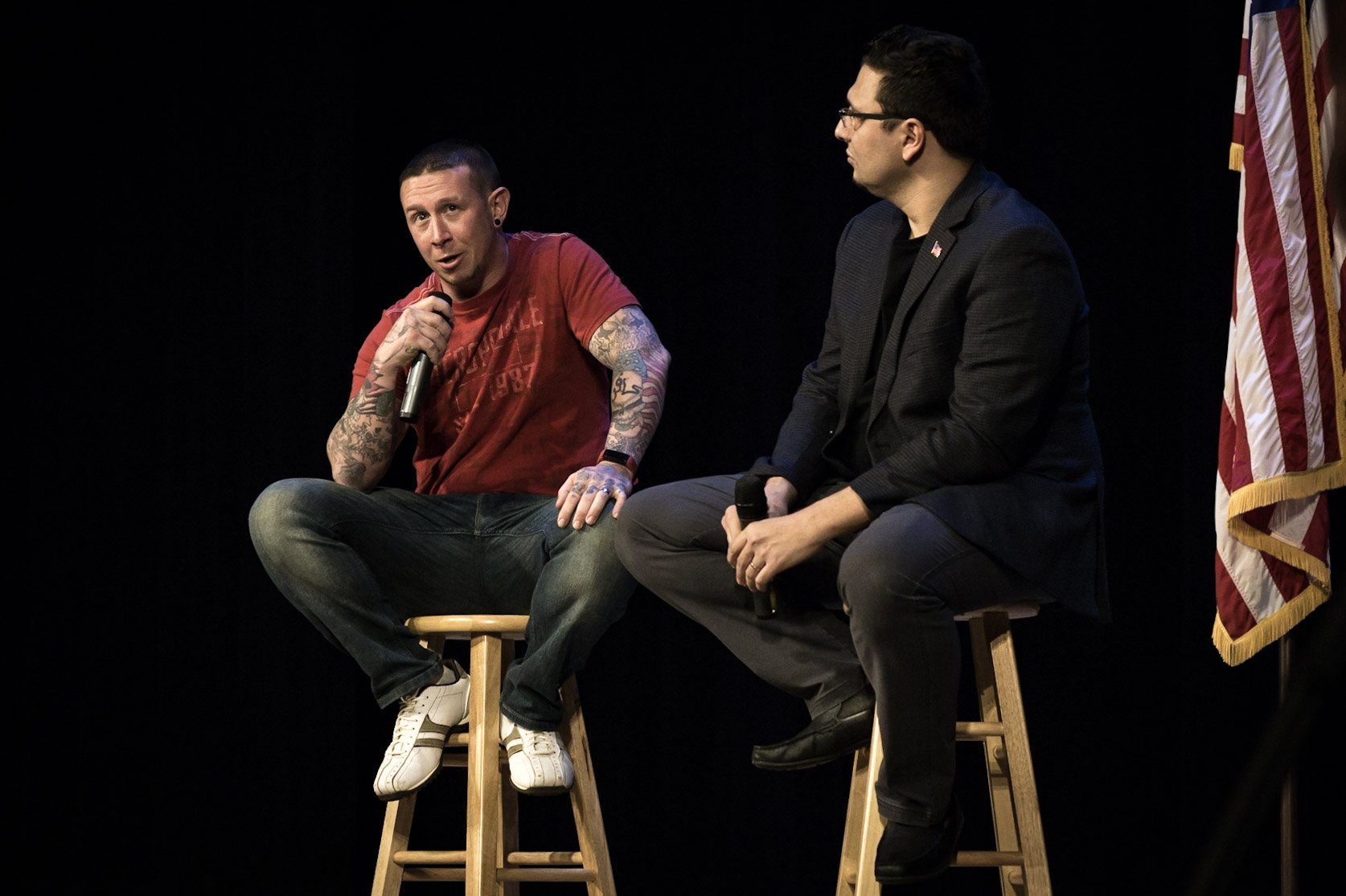 Two men speak on stage