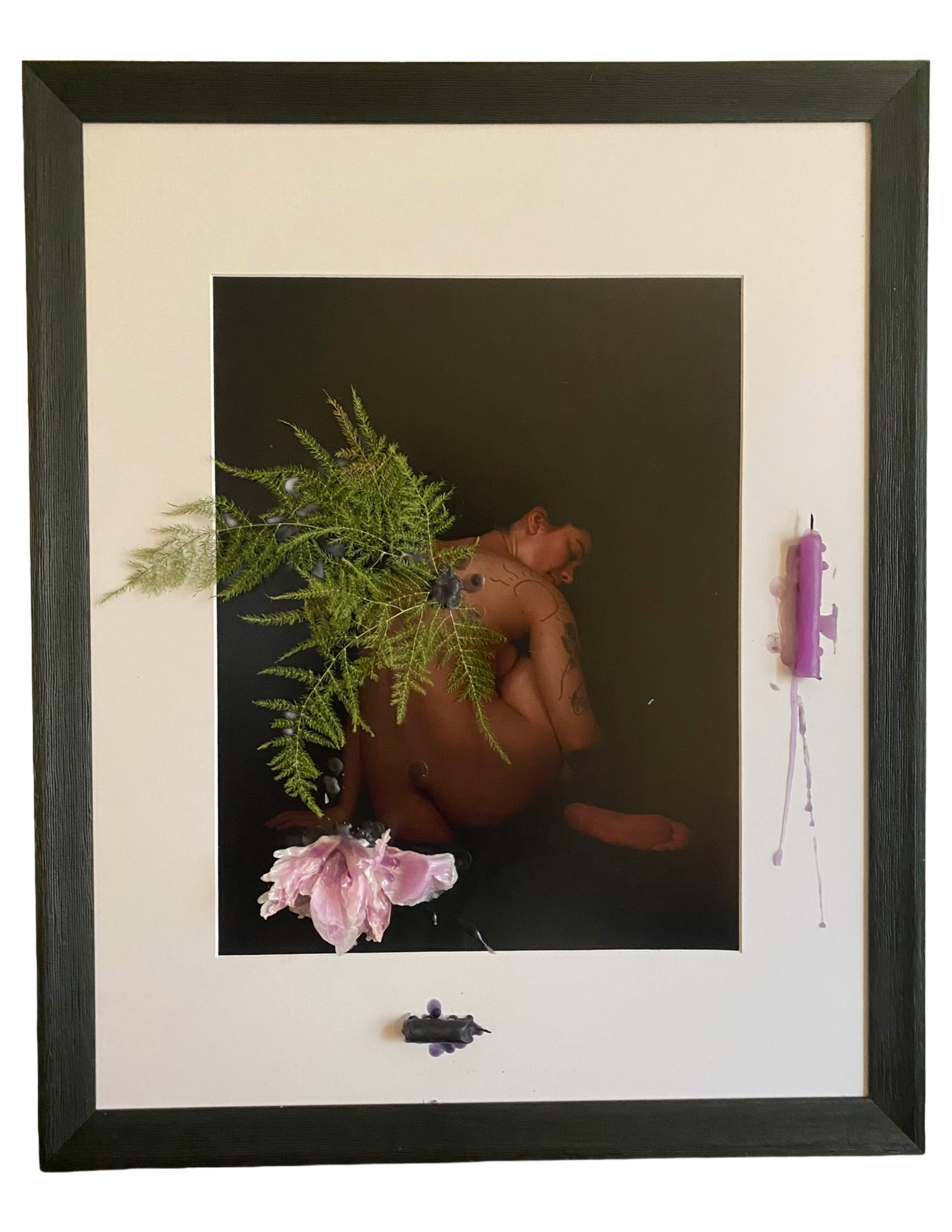 black frame with white mat holding artist self-portrait with fern leaves collage like wings and flowers both sealed onto the image with wax. the two candles used are sealed with their own wax on the right and bottom side.