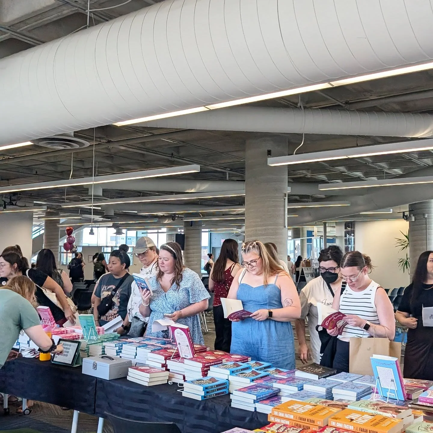 A row of people browsing at a book table during a gritLIT event.