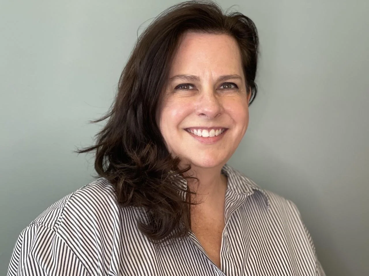 Smiling woman with dark hair wearing a striped shirt.