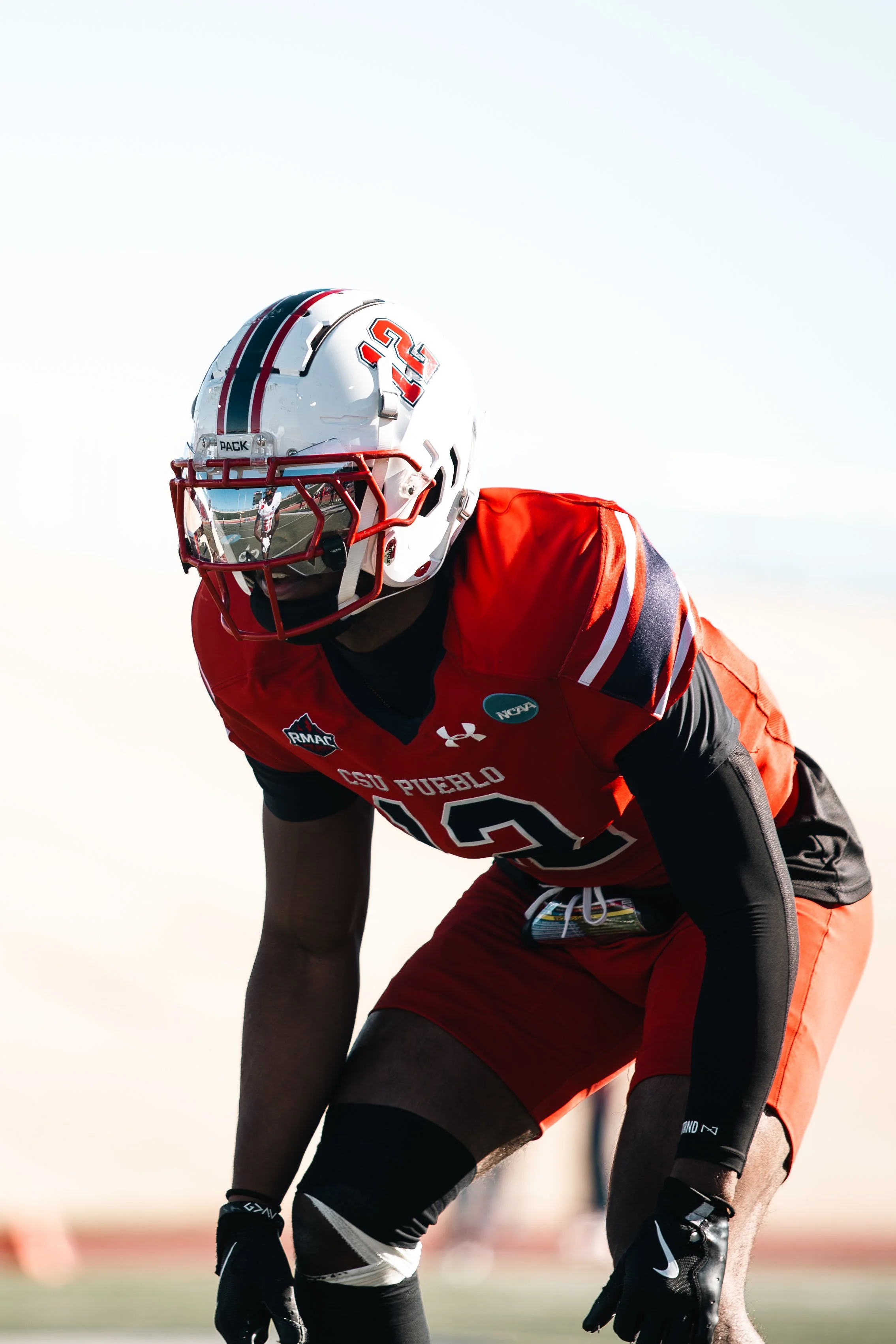 A football player in red and black uniform wearing helmet and pads on football field