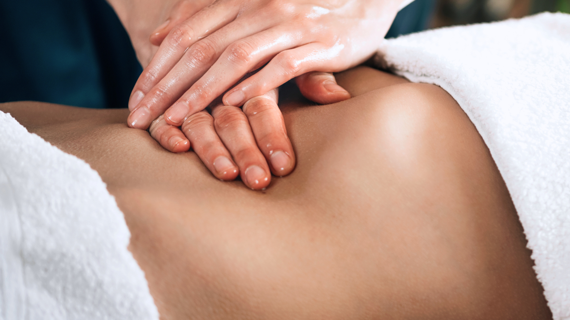 Close-up of a person receiving a brazilian lymphatic drainage massage with oil, lying on a white towel, in clinic in Hampstead, London.