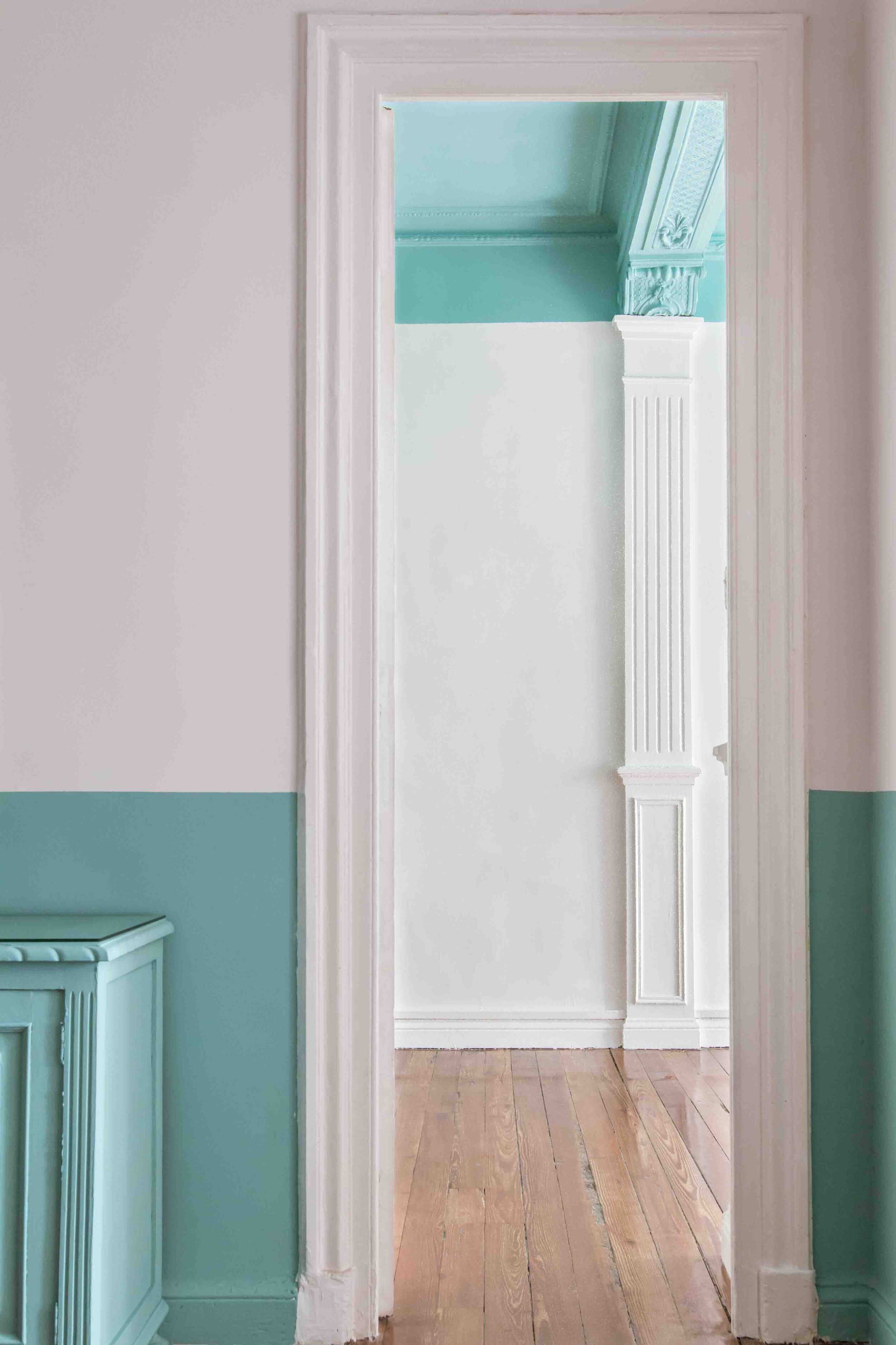 Puerta que conecta dos habitaciones decoradas en tonos claros, con paredes blancas y detalles en azul y madera en el piso.