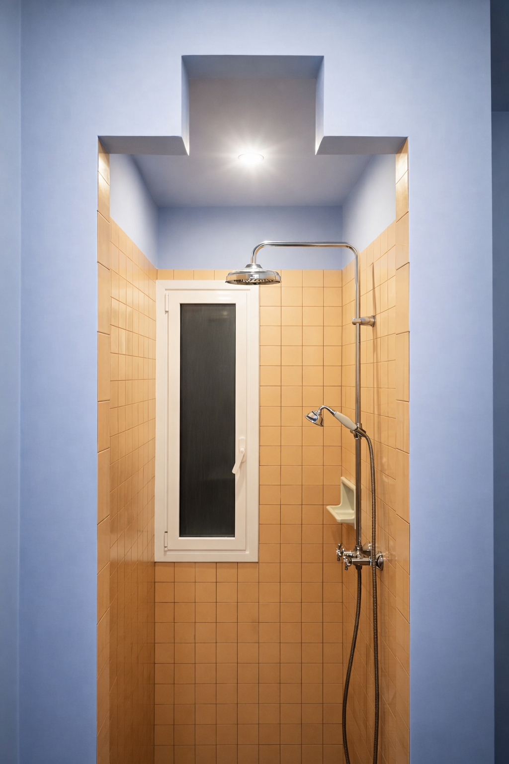 Ducha dentro de un baño con paredes de azulejo color durazno y paredes azules, con una ventana blanca y una ducha de ducha fija y de mano.