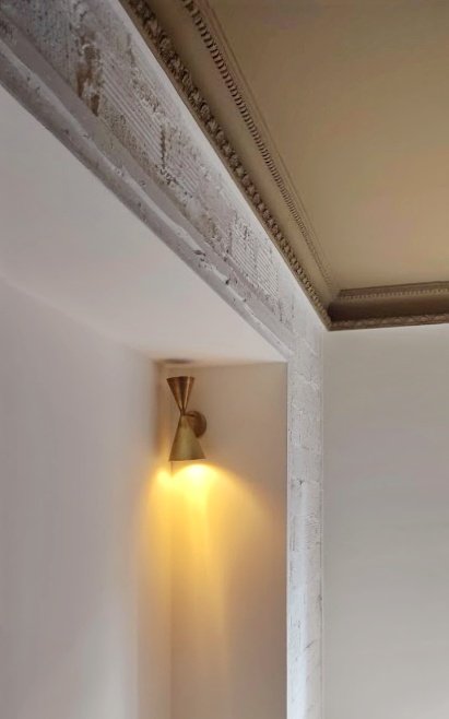 Luz empotrada en la pared dirigida hacia abajo, en una habitación con detalles decorativos en el techo.